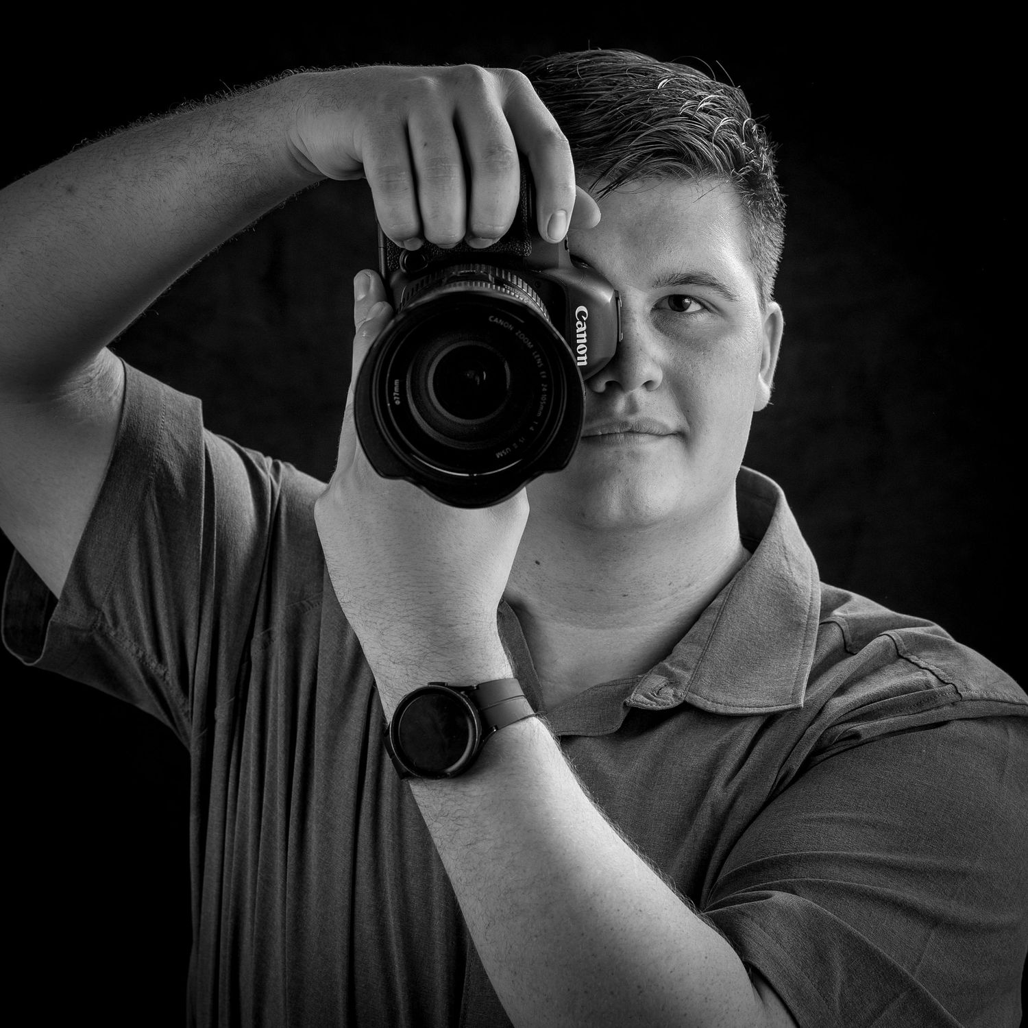 Professional photographer demonstrates camera technique in black and white studio shot.
