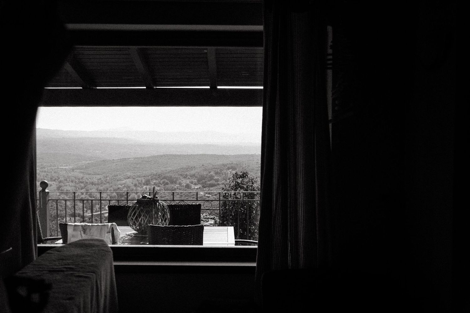 A window view overlooking a distant cityscape in black and white.