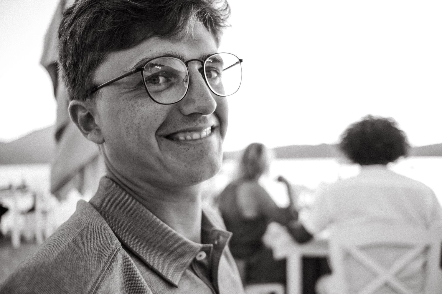 Black and white portrait of someone smiling at an outdoor gathering.