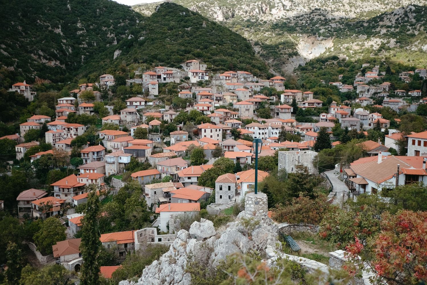 Picturesque hillside village with traditional red-roofed houses nestled in the mountains of Greece.