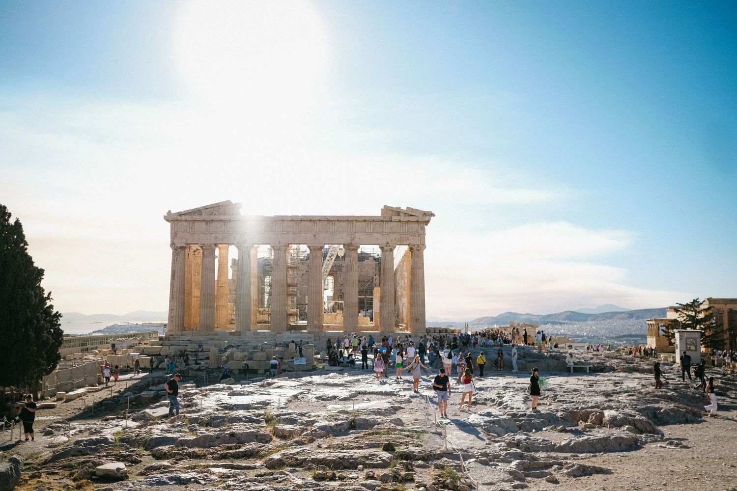Visitors explore the iconic Parthenon temple ruins on the Acropolis during a sunny day.