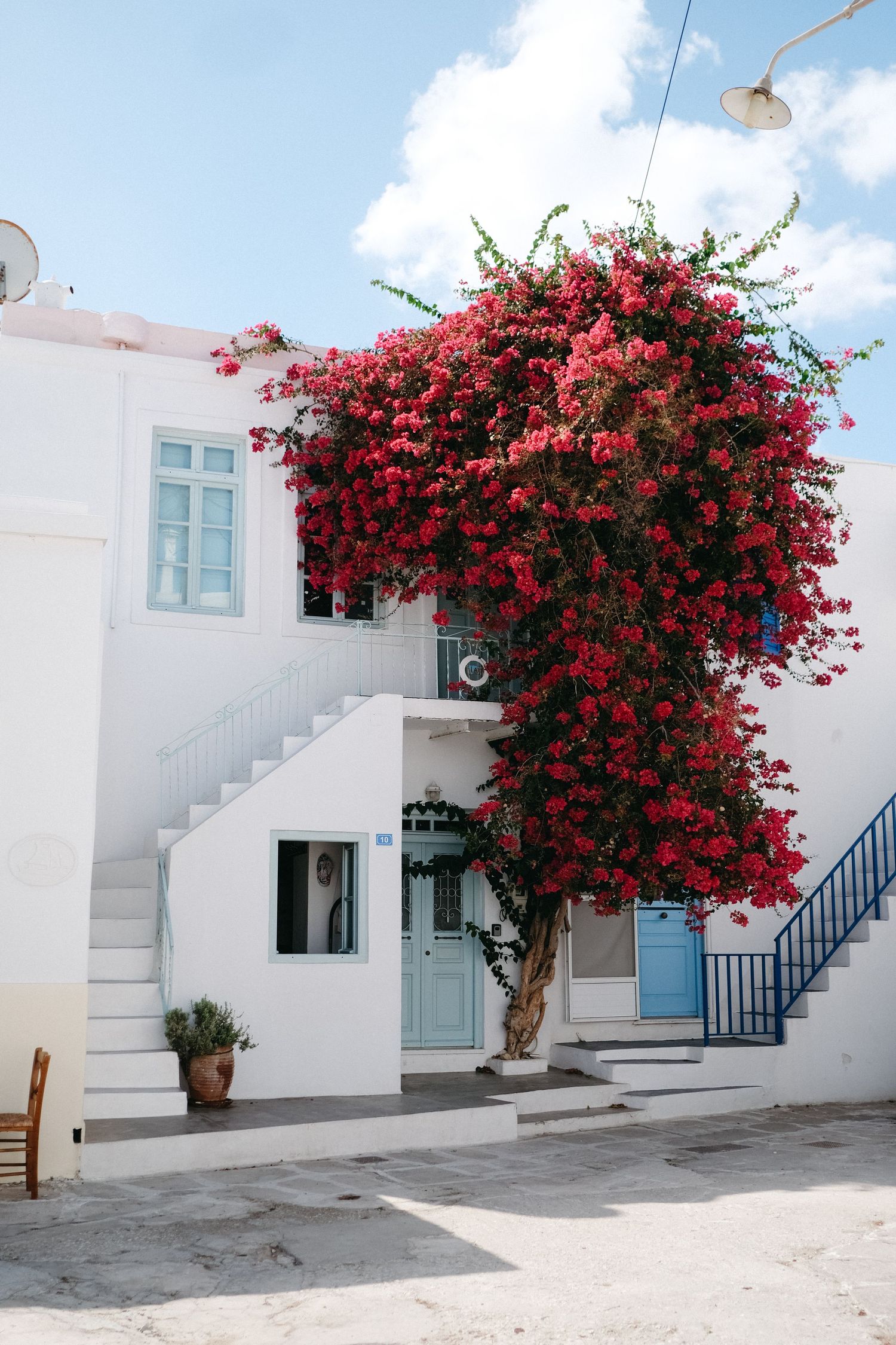 Mediterranean white building with vibrant pink bougainvillea cascading down the facade.