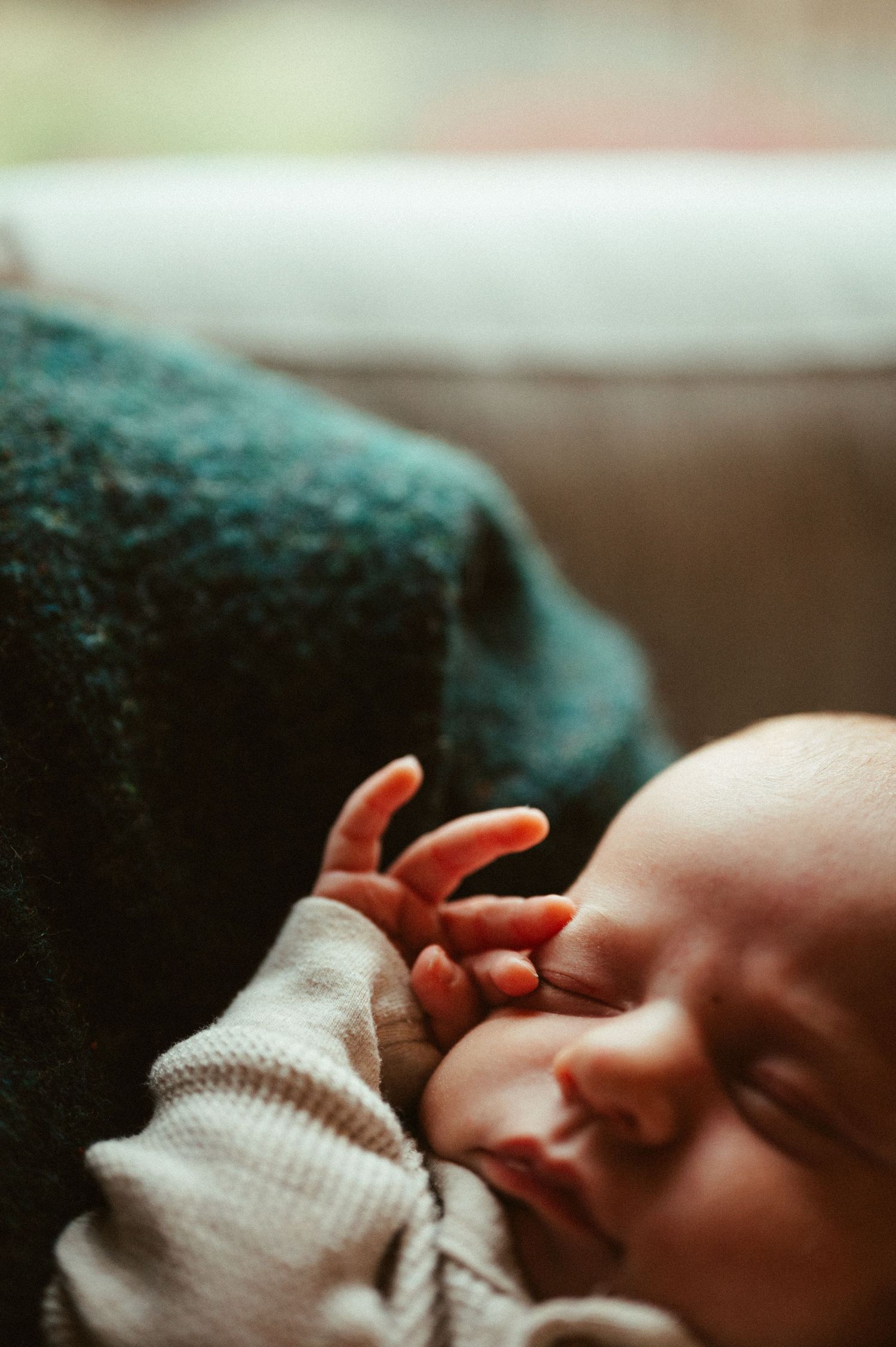 Close-up photo of a sleeping newborn baby wrapped in a white blanket.