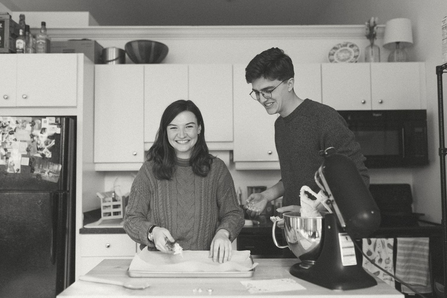 A couple preparing food together in a black and white kitchen scene.