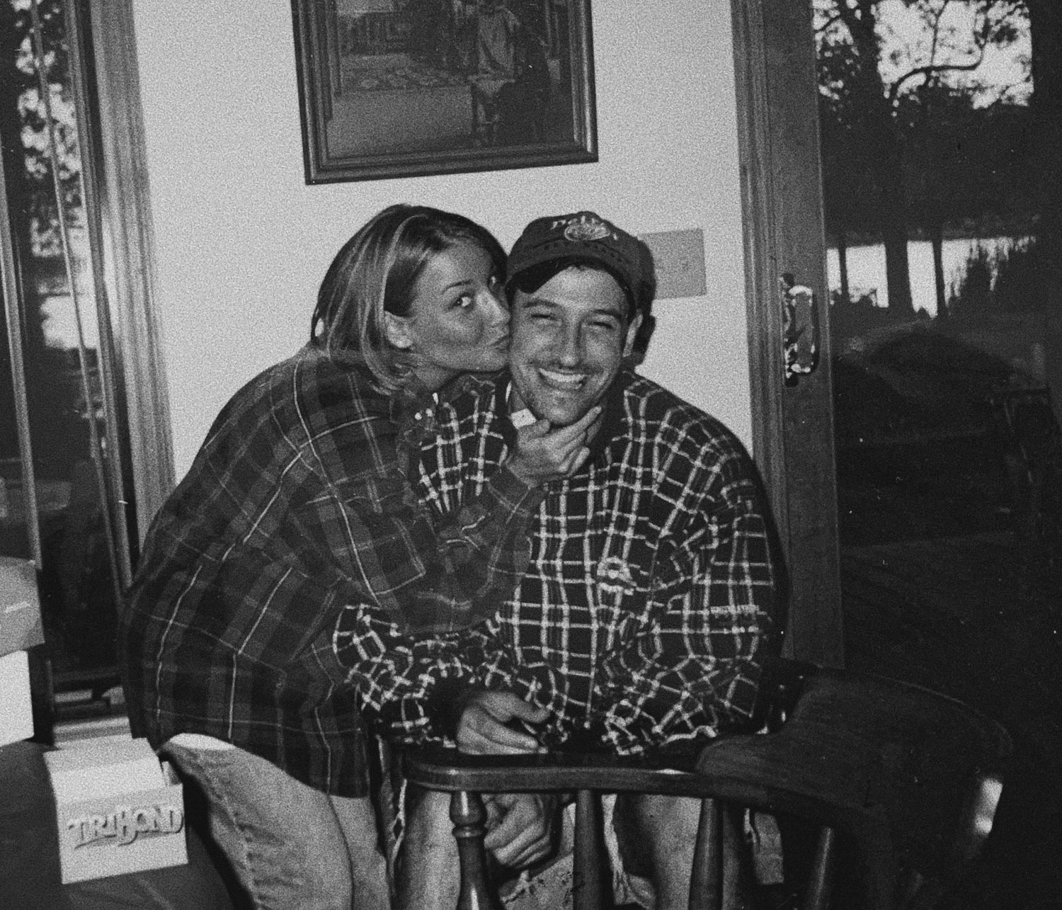 Couple in plaid shirts sharing an affectionate moment indoors.