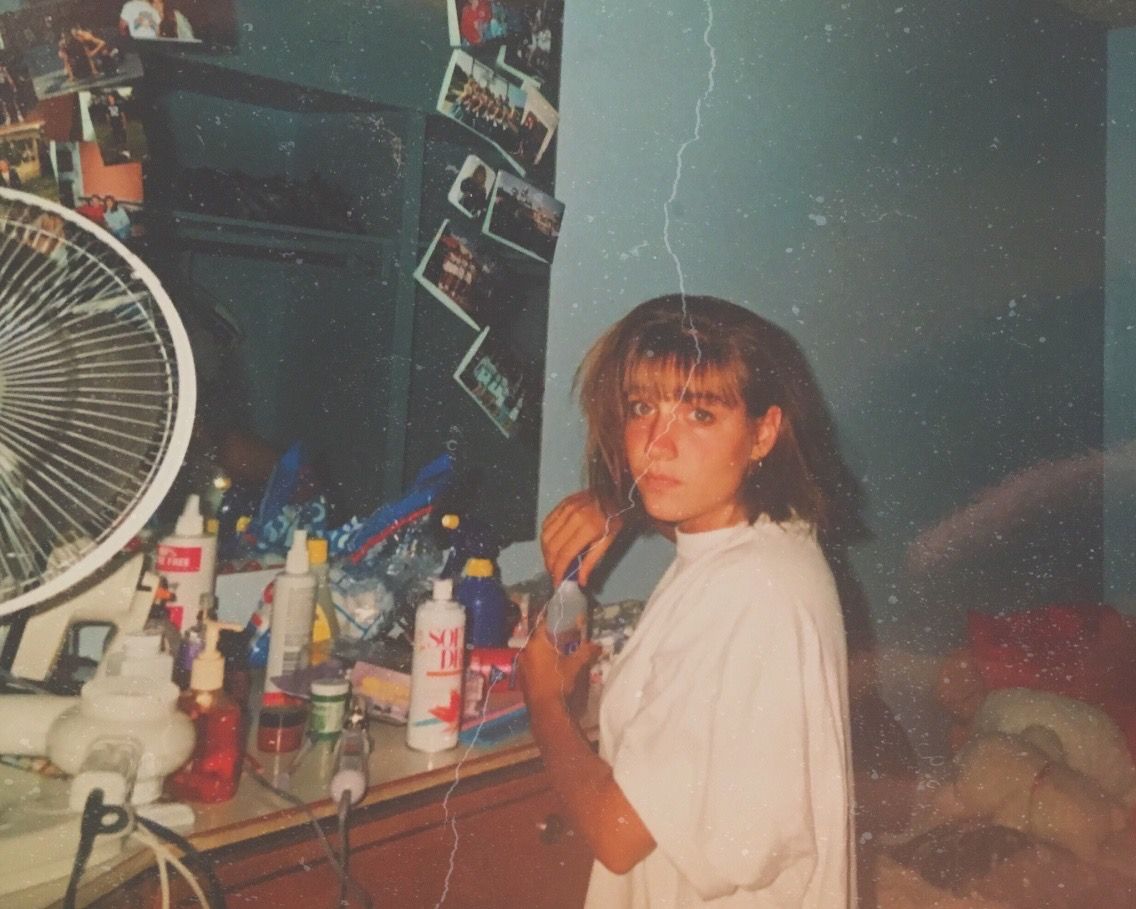A vintage photograph showing bottles and personal items on a cluttered shelf with a fan.