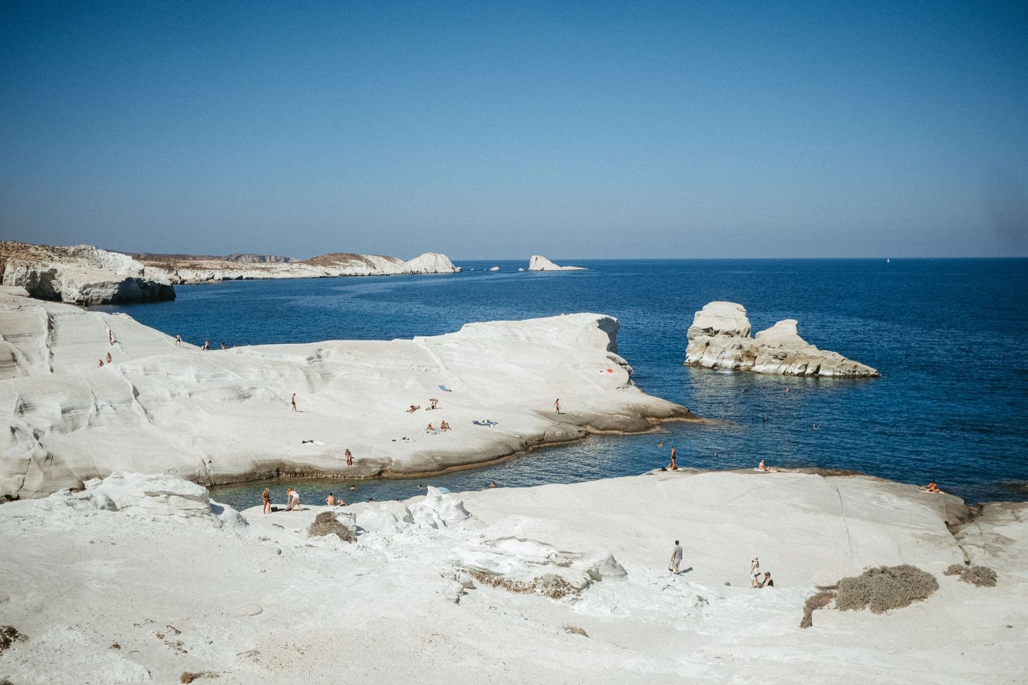 White limestone formations and cliffs along Mediterranean coastline under bright blue sky.