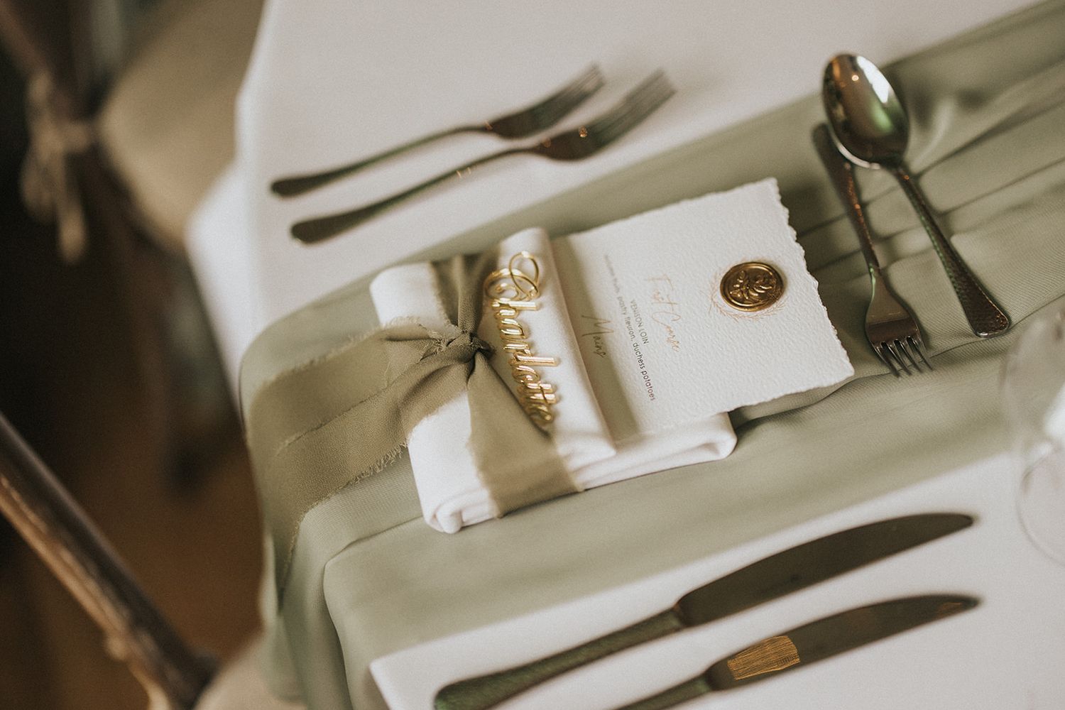 Elegant wedding place setting with cream linen napkin, utensils, and personalised enclosure card on white tablecloth at Laceby Manor.