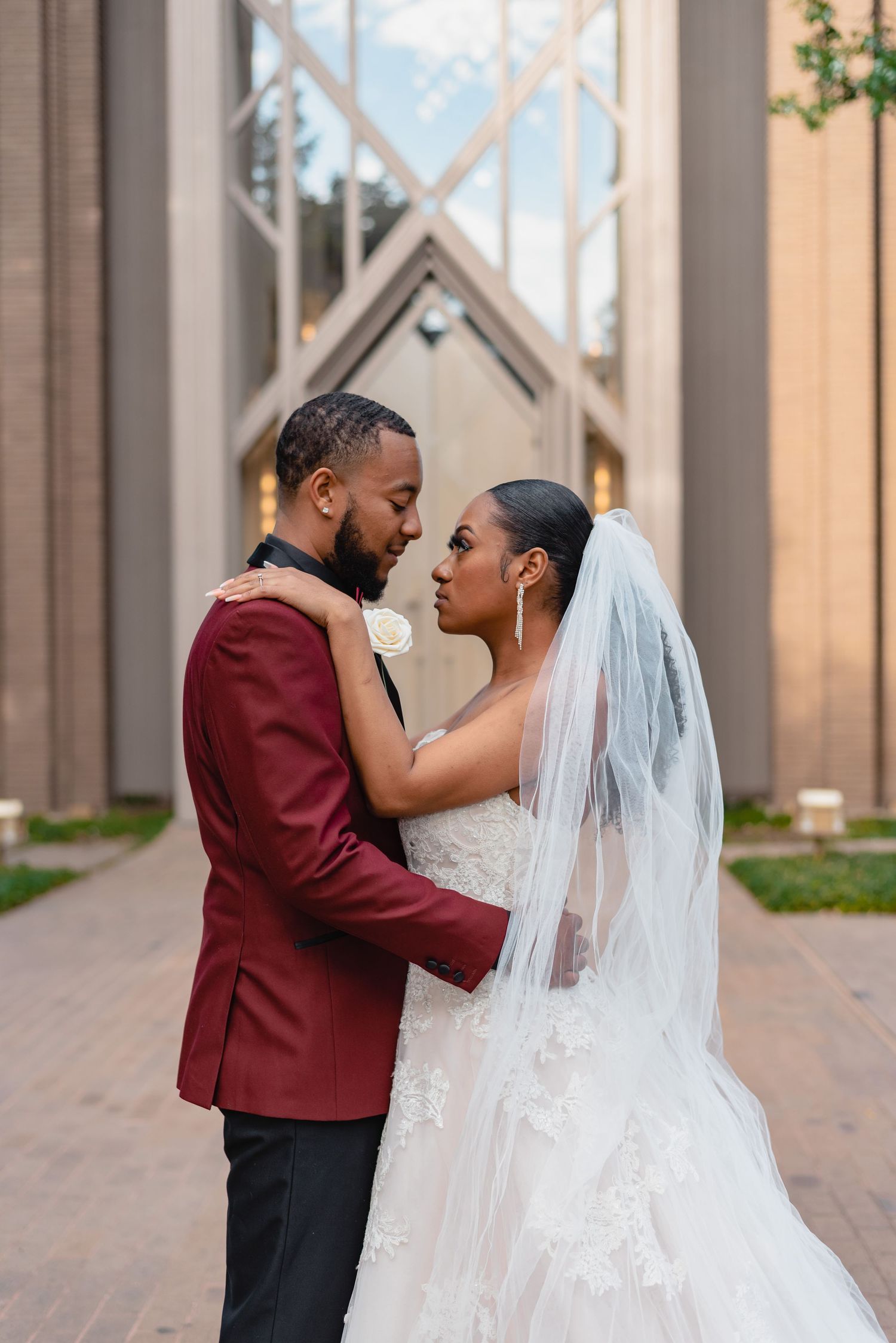Couple in wedding attire sharing an intimate moment near architectural columns.