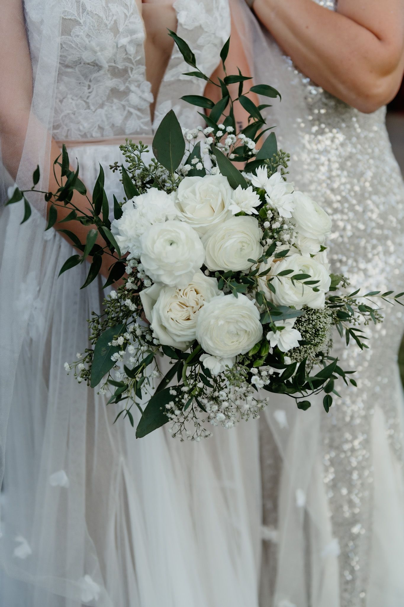 Elegant white rose bridal bouquet with green foliage and delicate baby's breath.