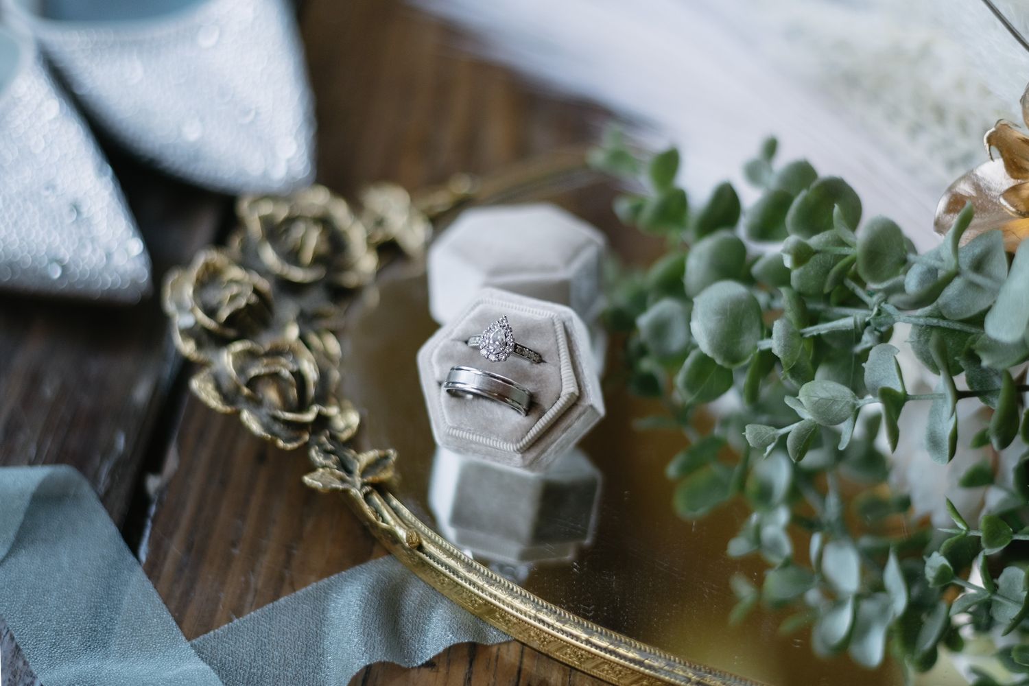 Close-up details of wedding decor featuring delicate floral arrangements and greenery on wooden surfaces.