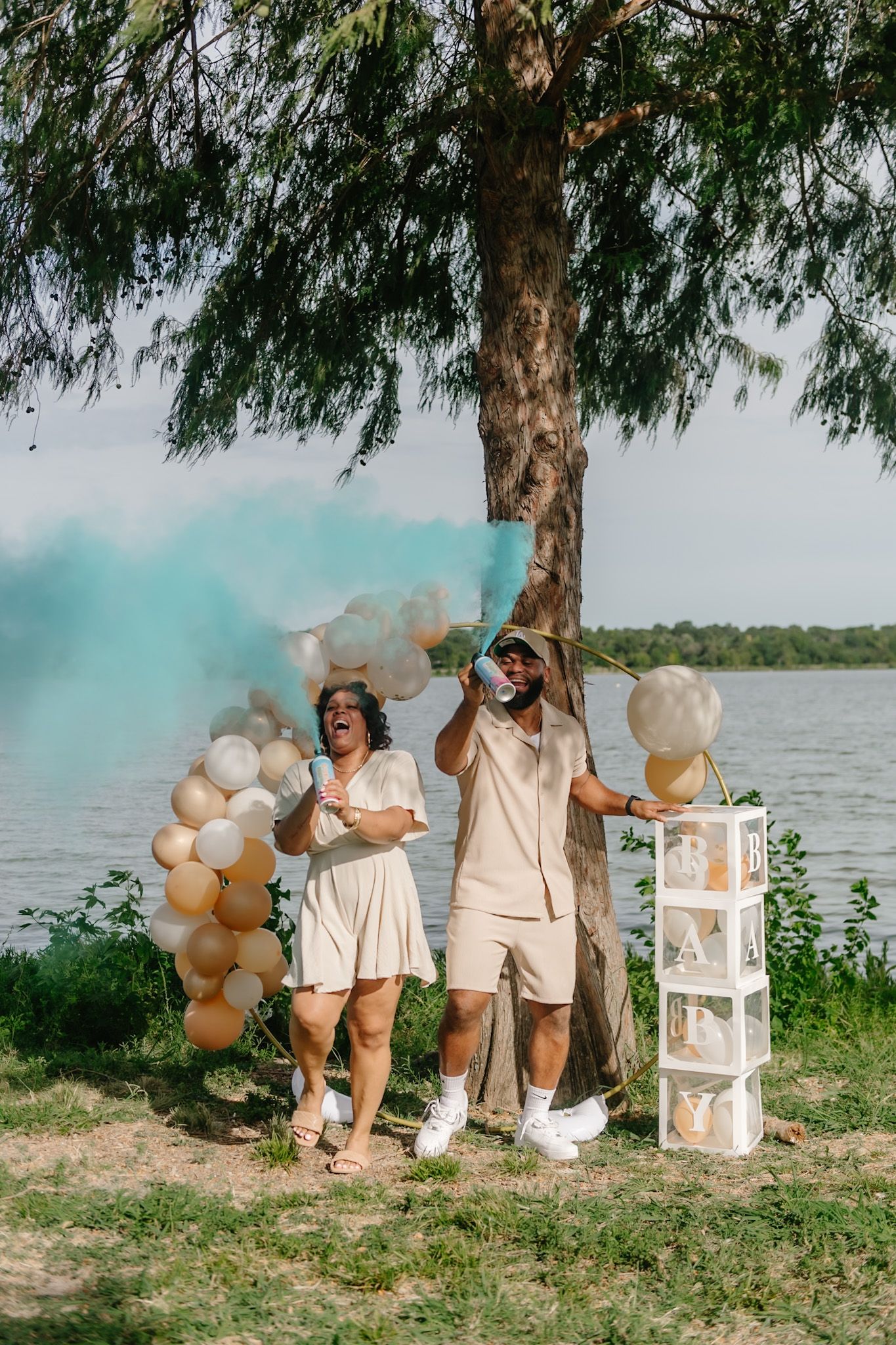 A group photo session with neutral outfits and balloons by the water.