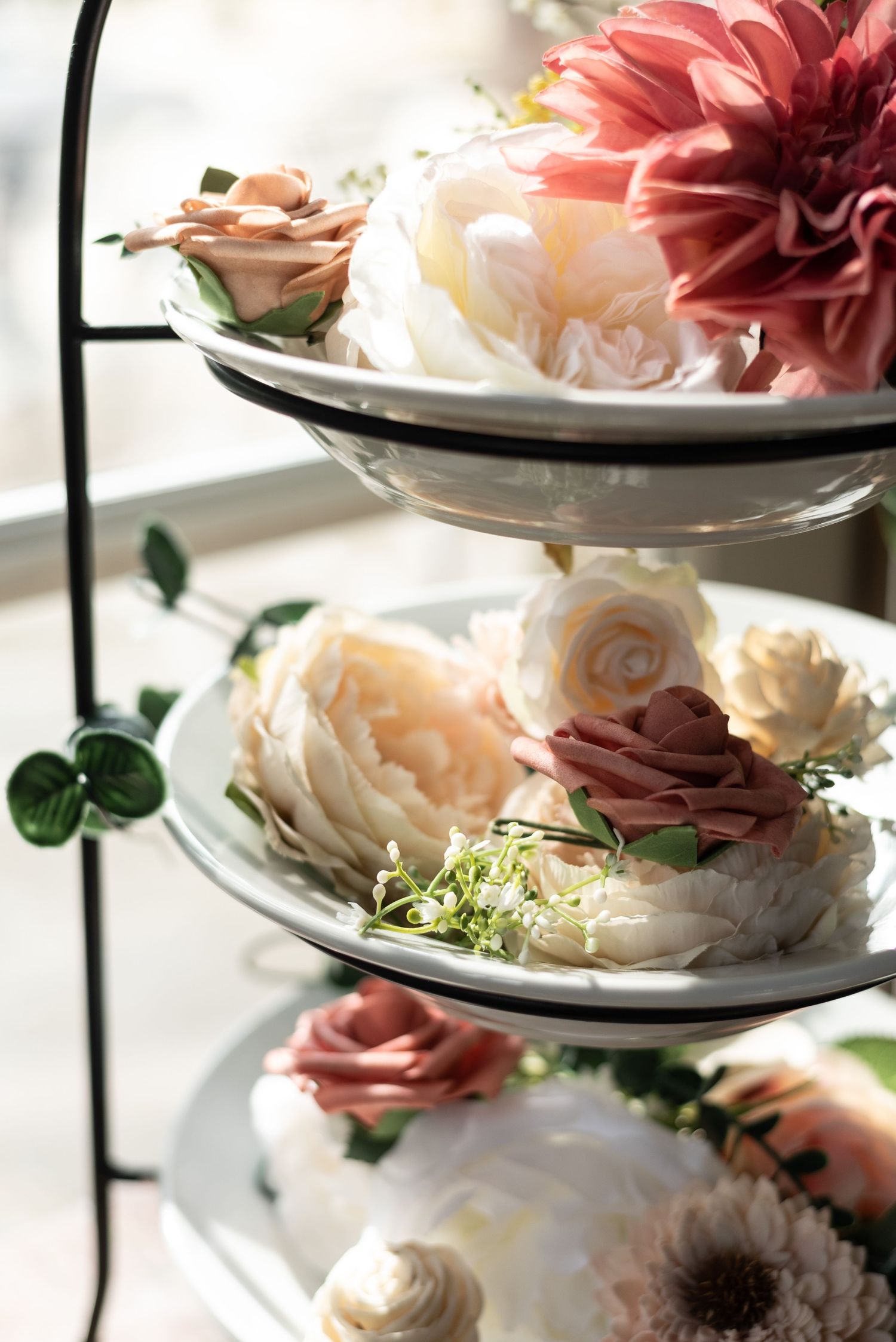 Delicate pink and white roses arranged on tiered plates creating an elegant table setting.