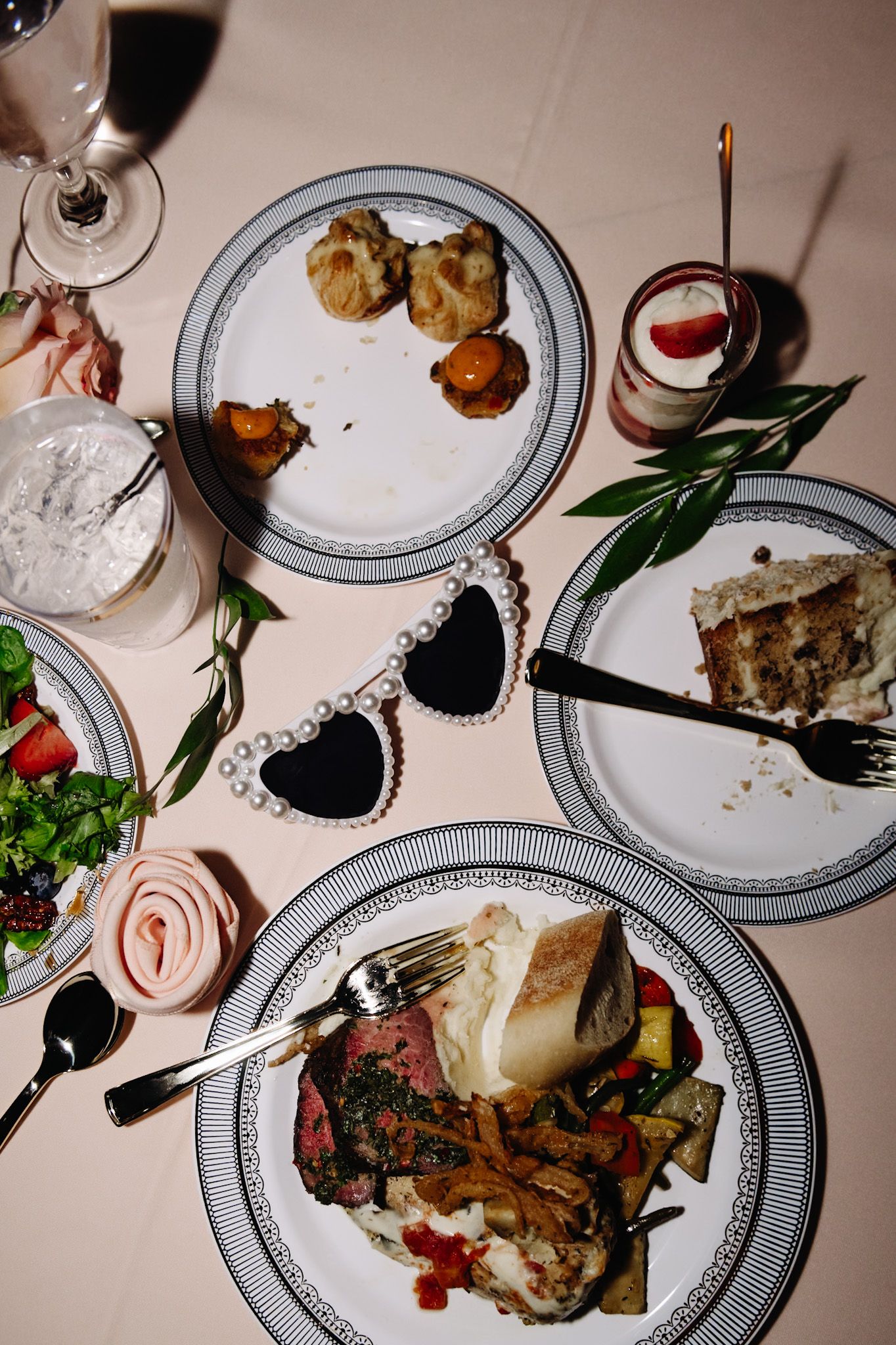 Elegant plated dinner dishes with meat and garnishes served on white plates with decorative black borders.