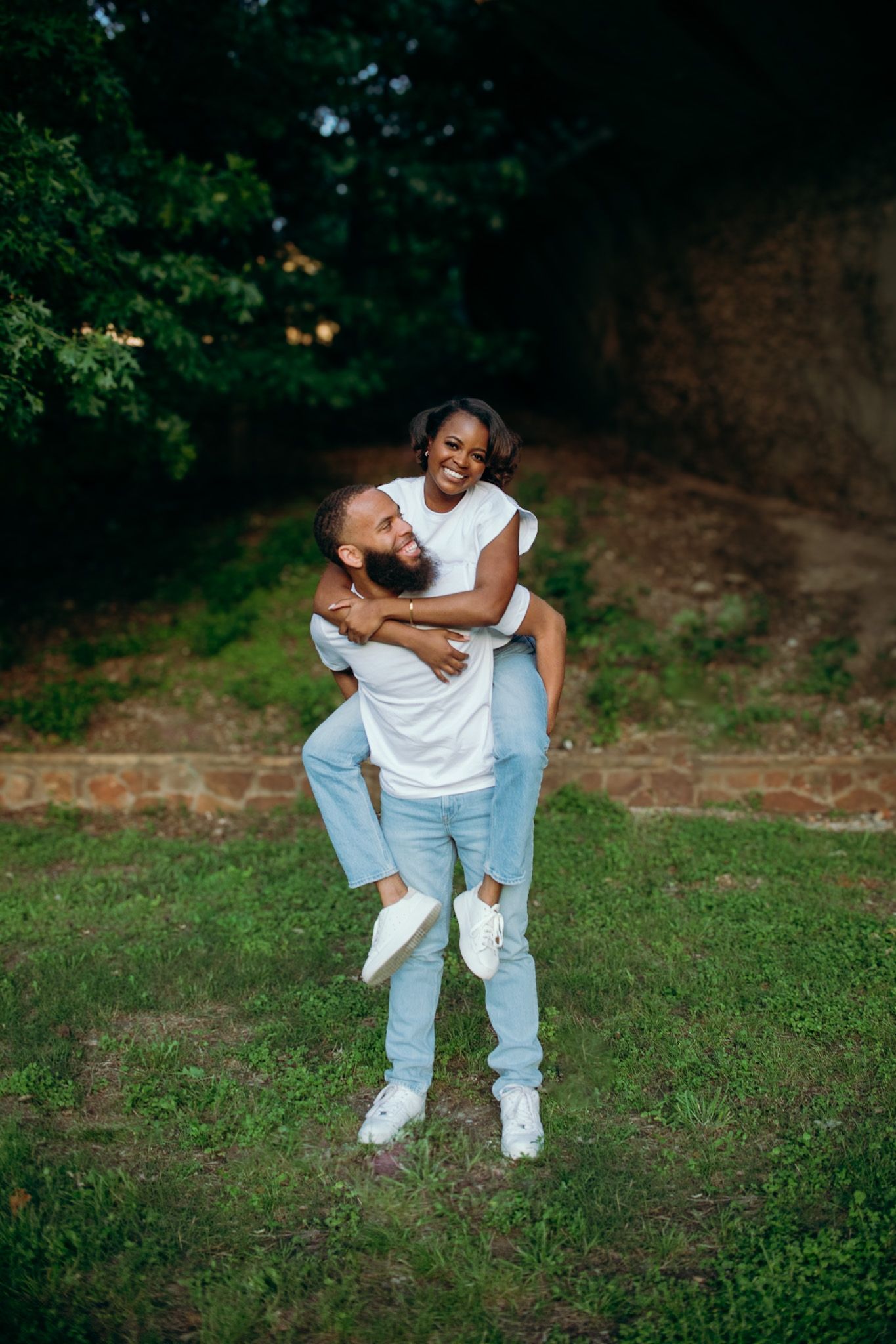 Playful couple in matching outfits share joyful moments on grassy terrain.