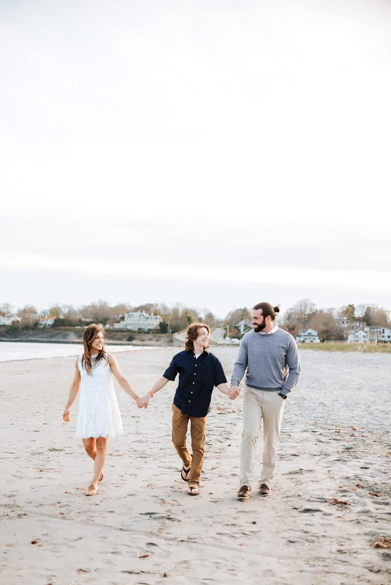 People strolling together on a sandy beach during a cloudy day.