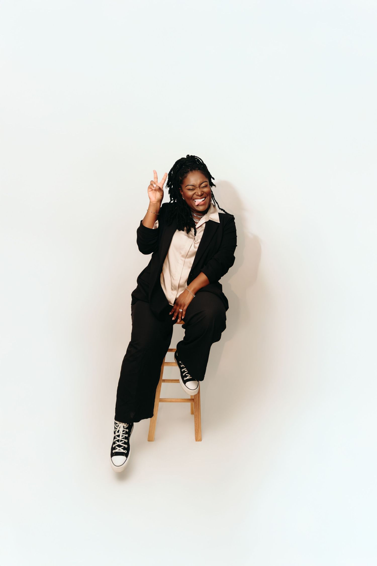 A person in black clothing poses playfully in four different positions against a white background.