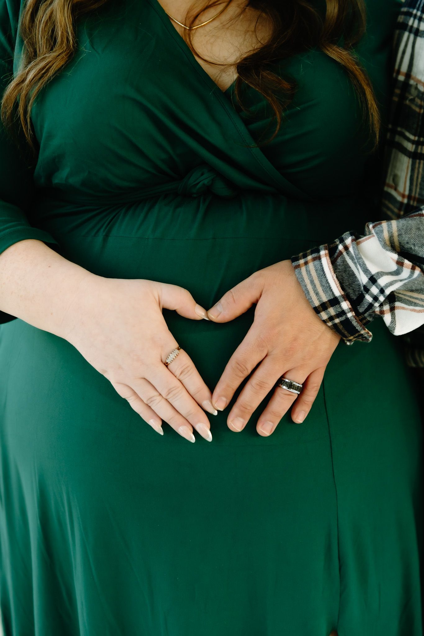 Close-up of hands wearing rings against an emerald green dress.