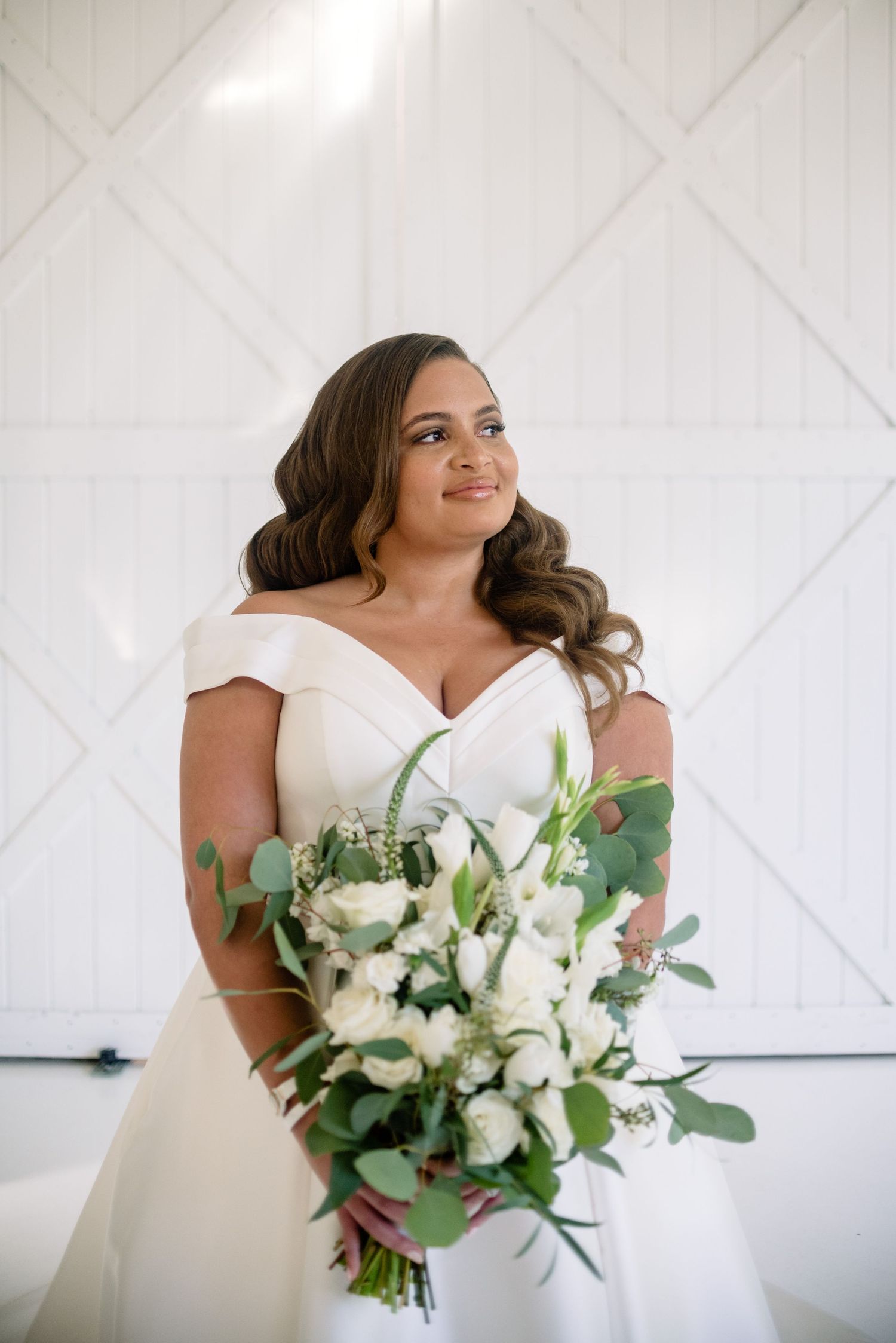 Elegant white bridal portrait session with a beautiful bouquet of white flowers and greenery.
