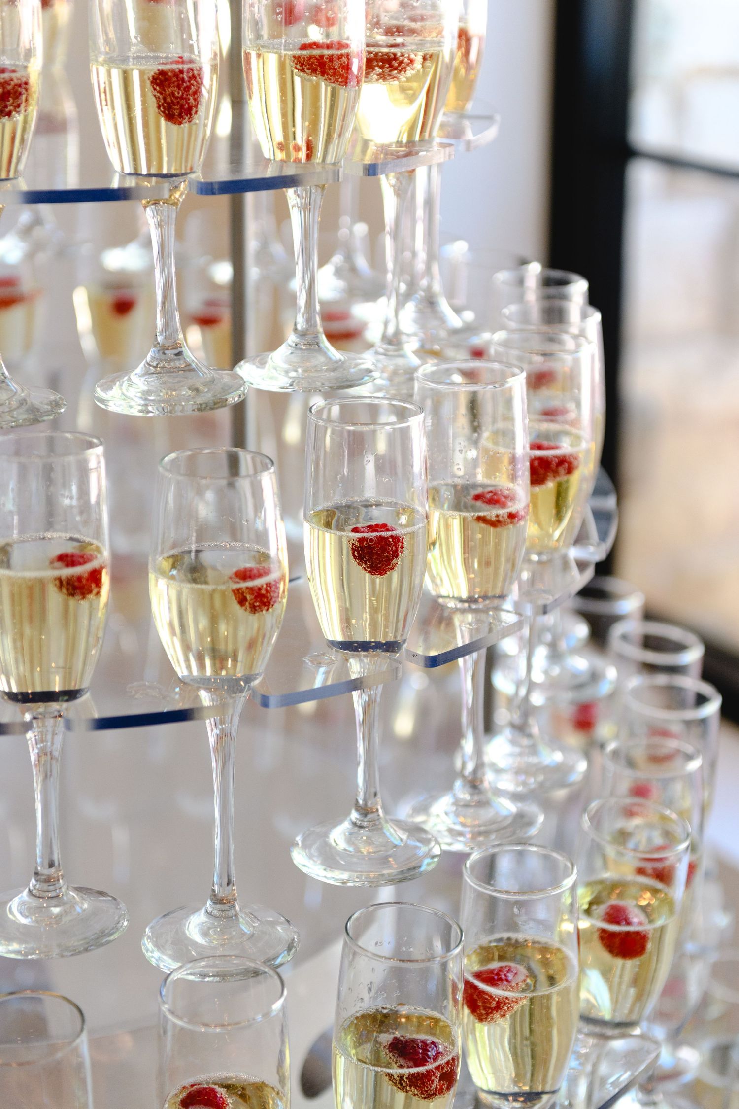Champagne glasses with fresh raspberries arranged in elegant rows for a wedding celebration.