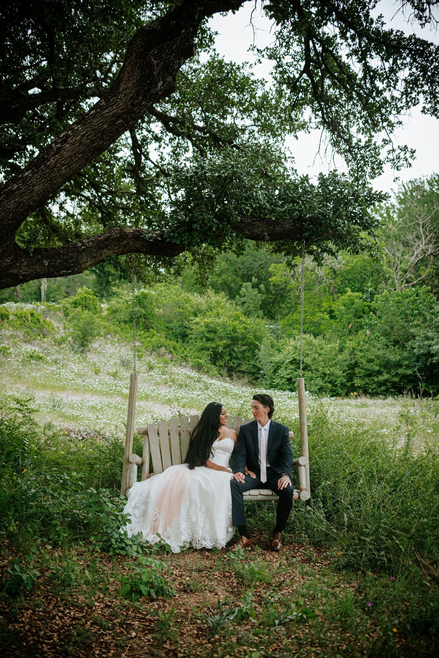 Wedding couple posing under a large tree in a natural outdoor setting.