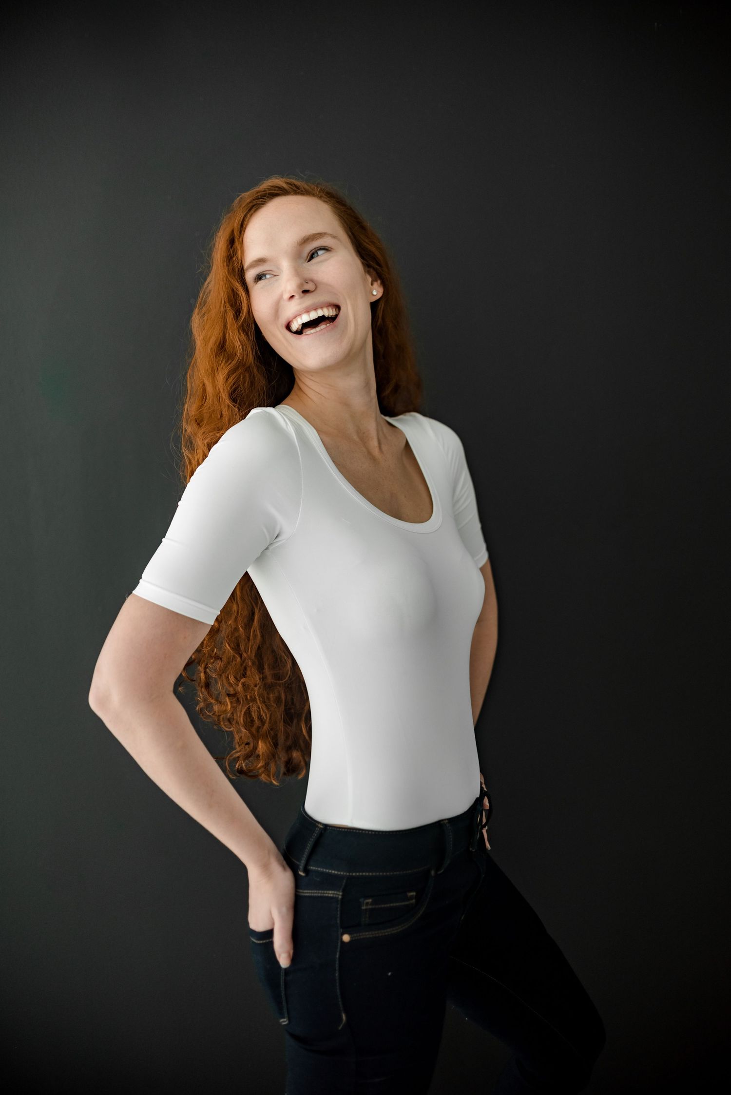 Portrait against dark background showing joyful movement and casual style.