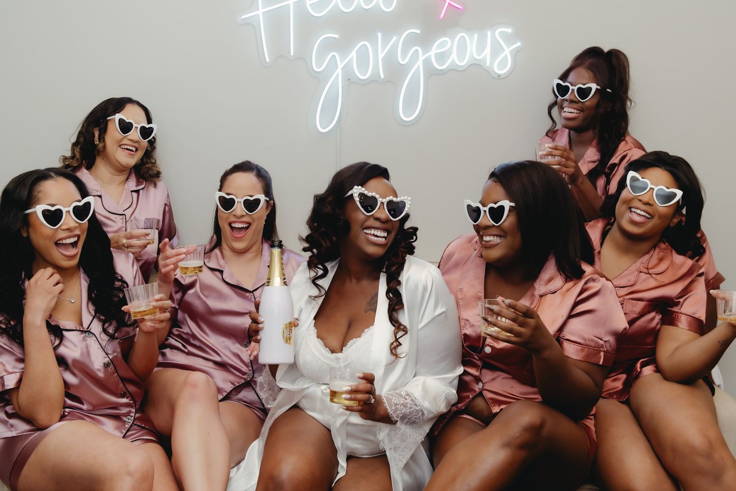 Group wearing sunglasses and pink outfits posing together outdoors.