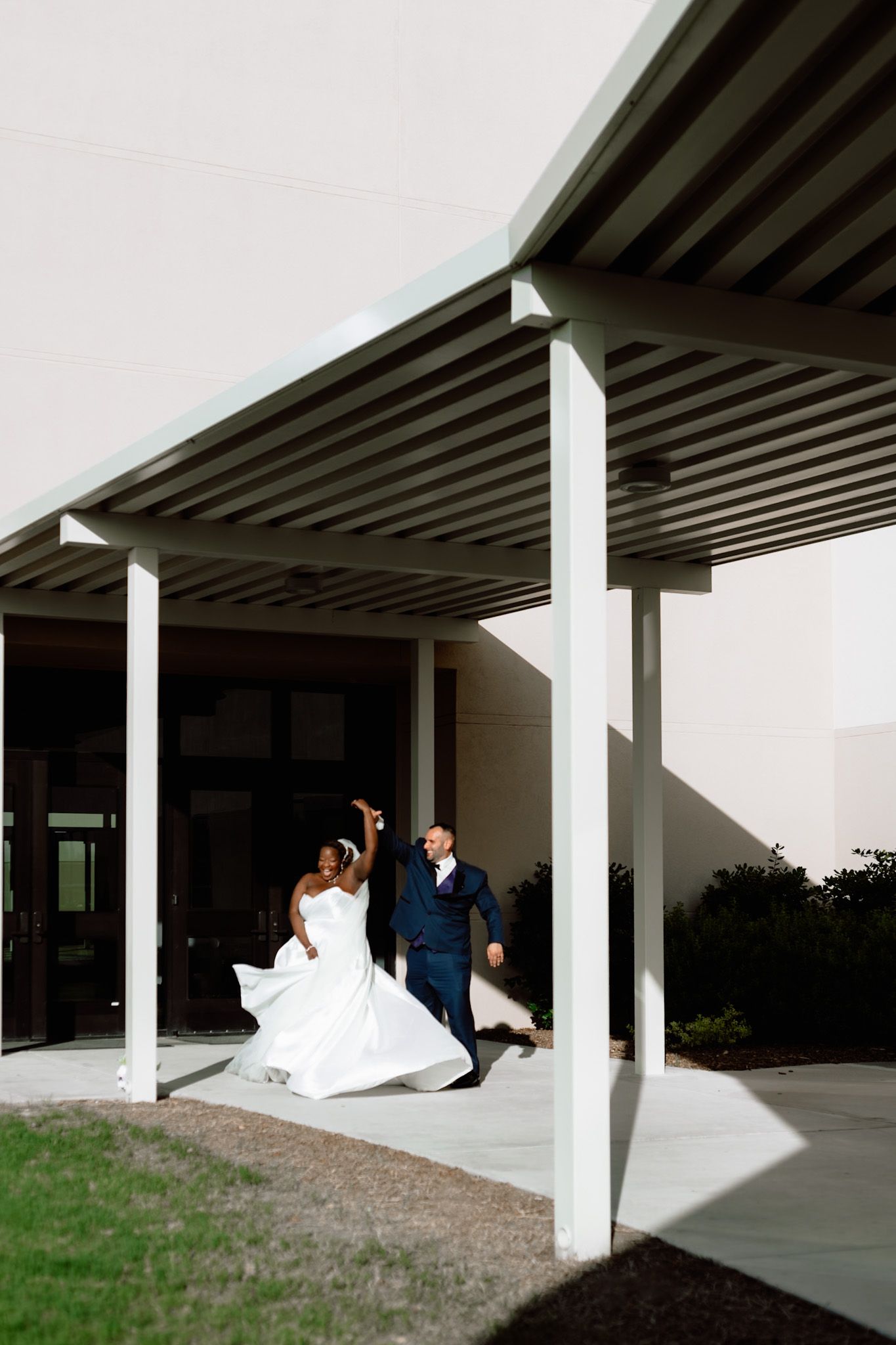 A couple dancing under a modern architectural overhang with white columns.