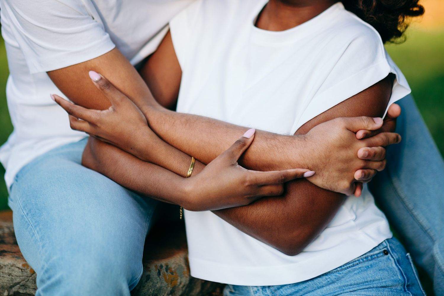 Couple in matching white shirts and light blue jeans embrace in a romantic outdoor photoshoot.