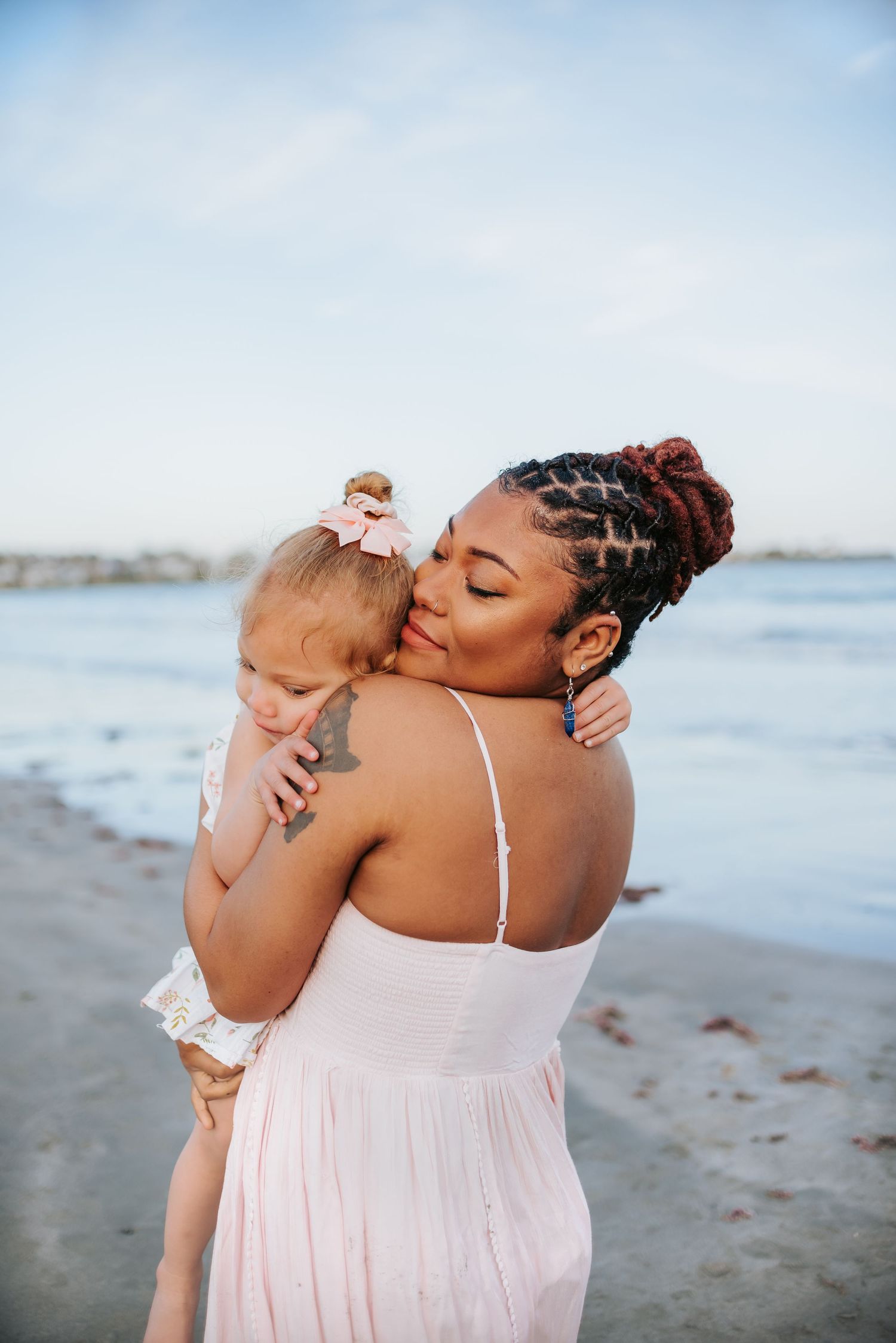 Mother and child sharing tender moments on sunny beach.