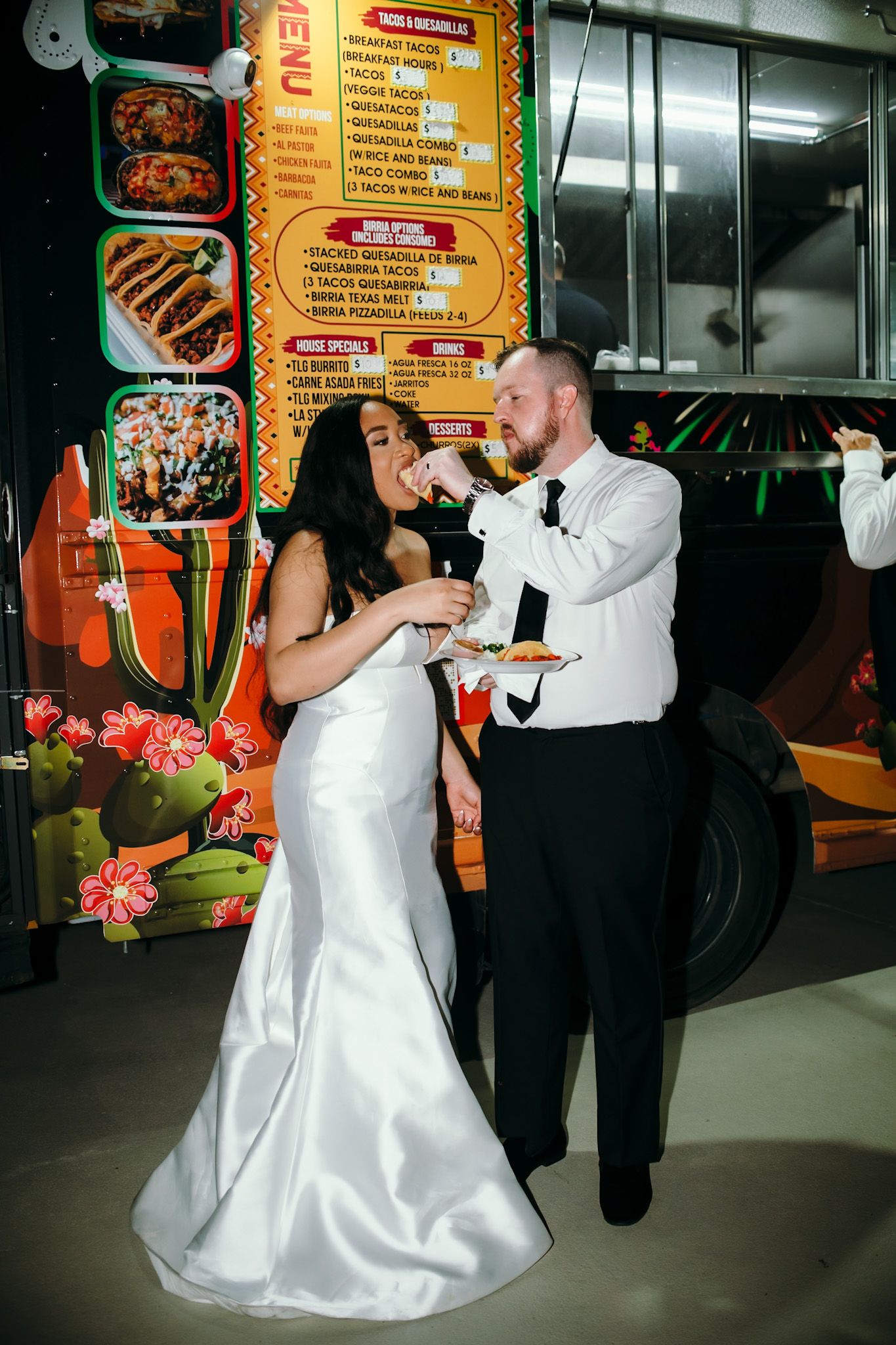 Newlyweds dancing together at a casual restaurant venue with menu boards visible in the background.