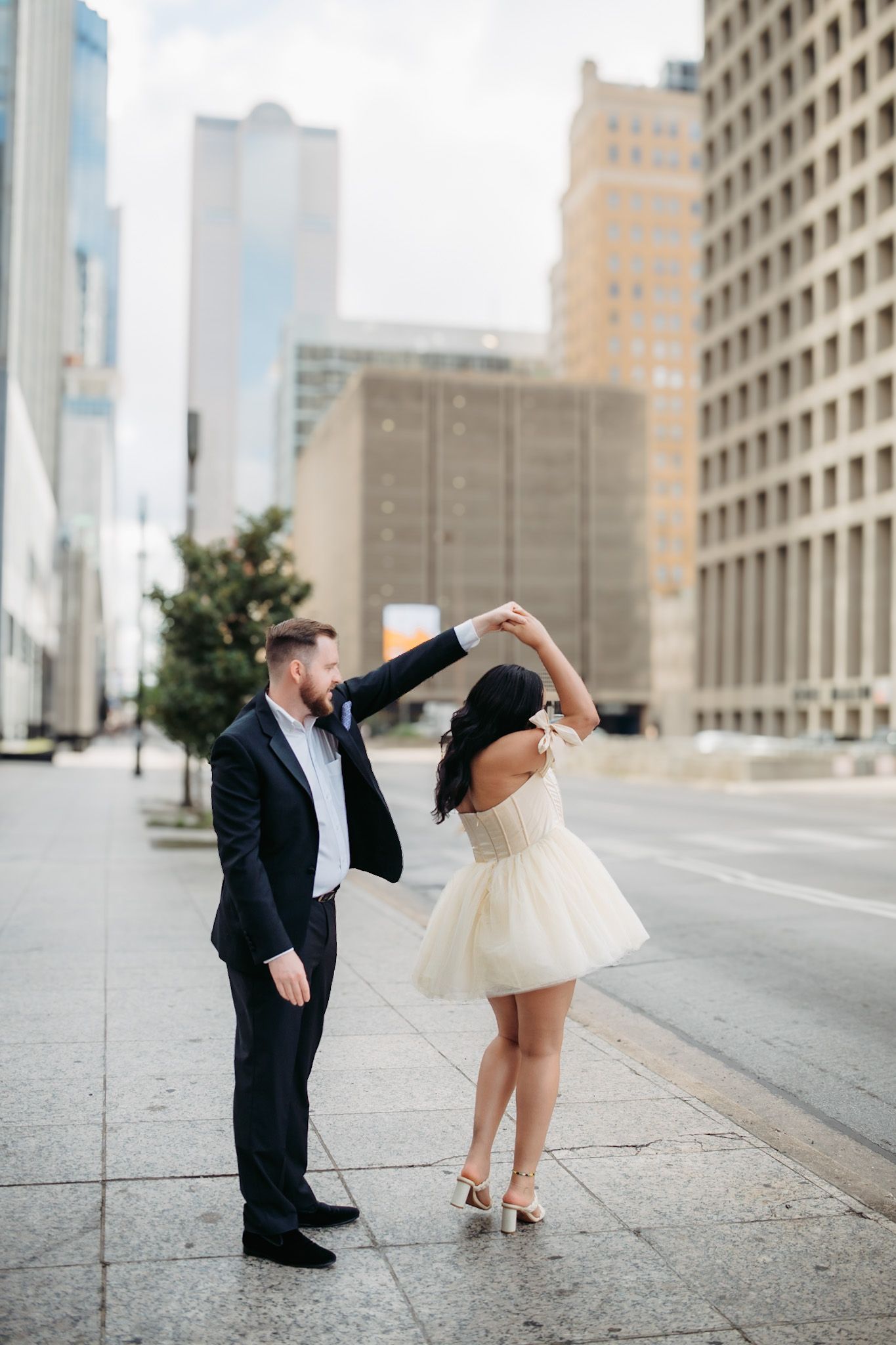 Urban engagement session with downtown architecture and playful dance poses.