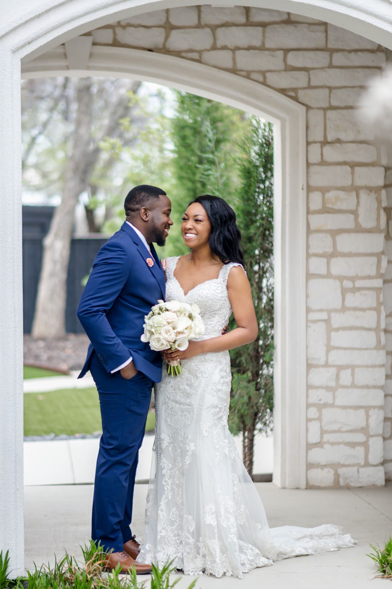 A romantic moment captured under a stone archway during a wedding.