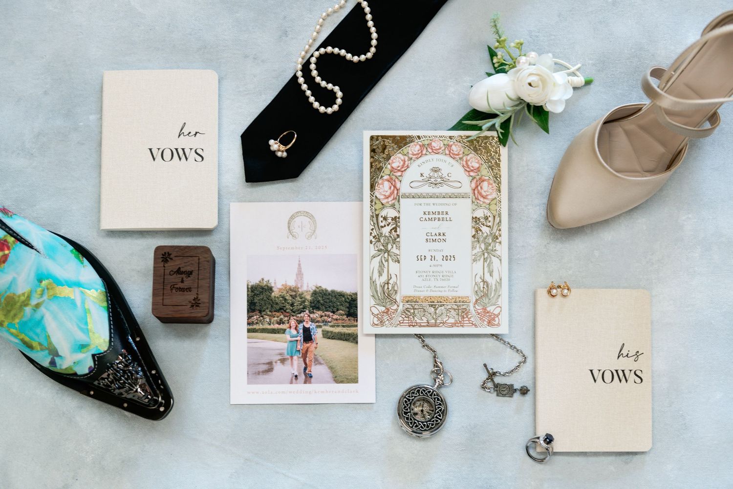 Flat lay of wedding vow books, jewelry, and elegant shoes with floral invitation.