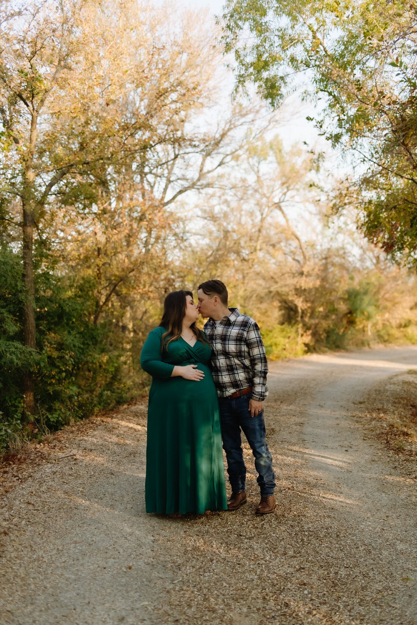 Couple walking together on a gravel path surrounded by autumn trees.
