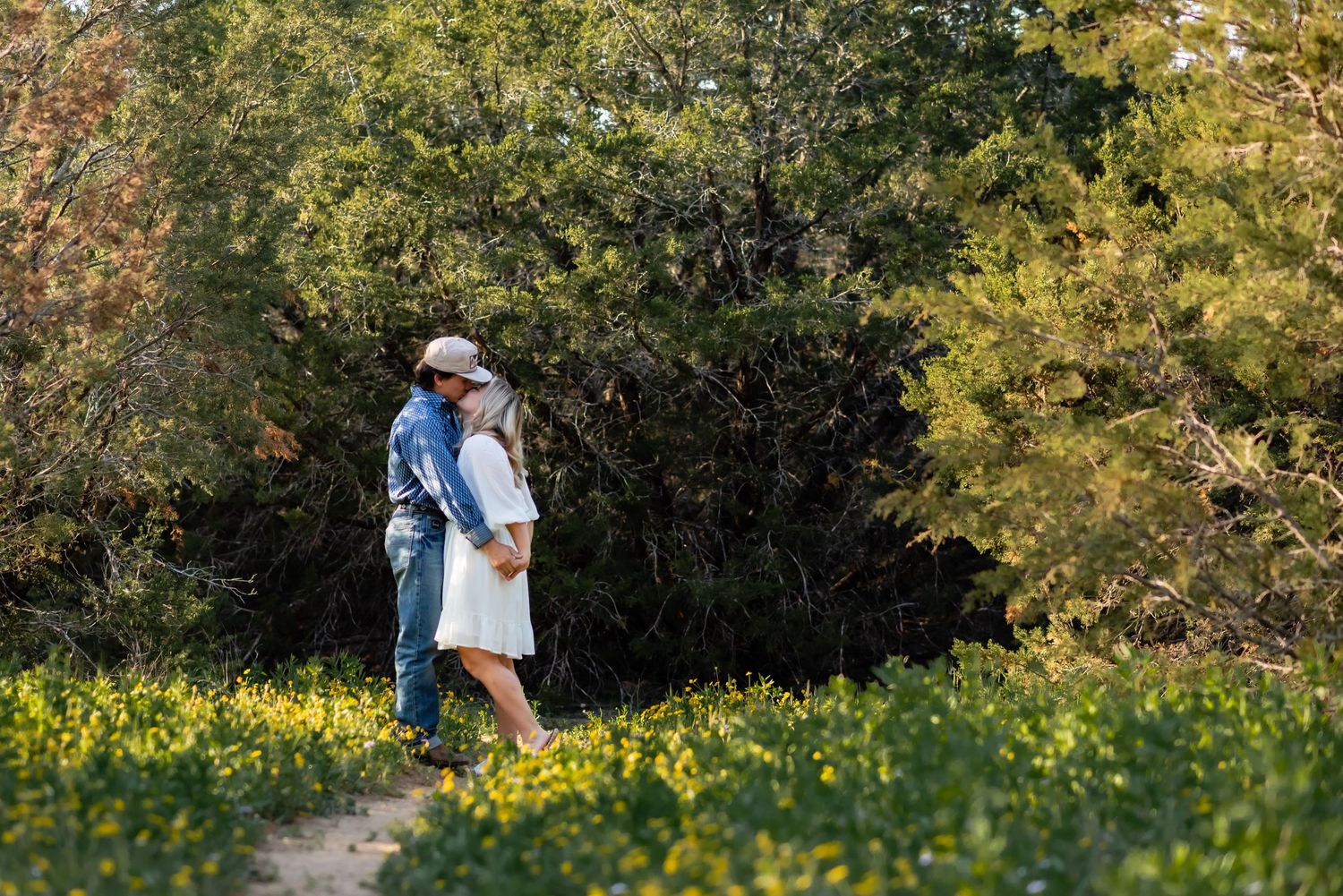 Couple walks through lush garden setting with golden sunlight filtering through trees.