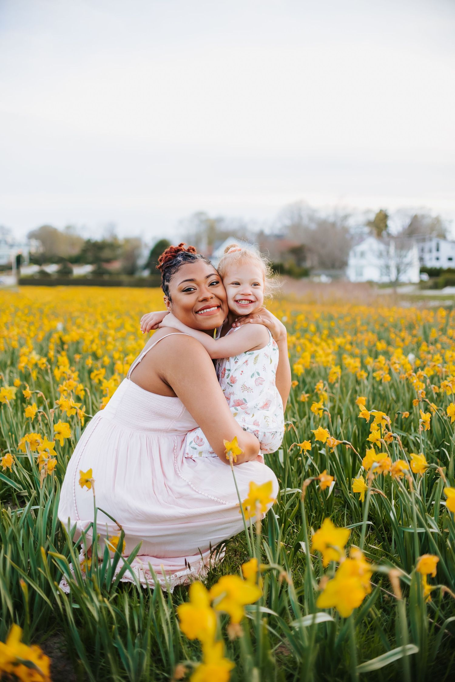 Mother and child posing in blooming yellow daffodil field.