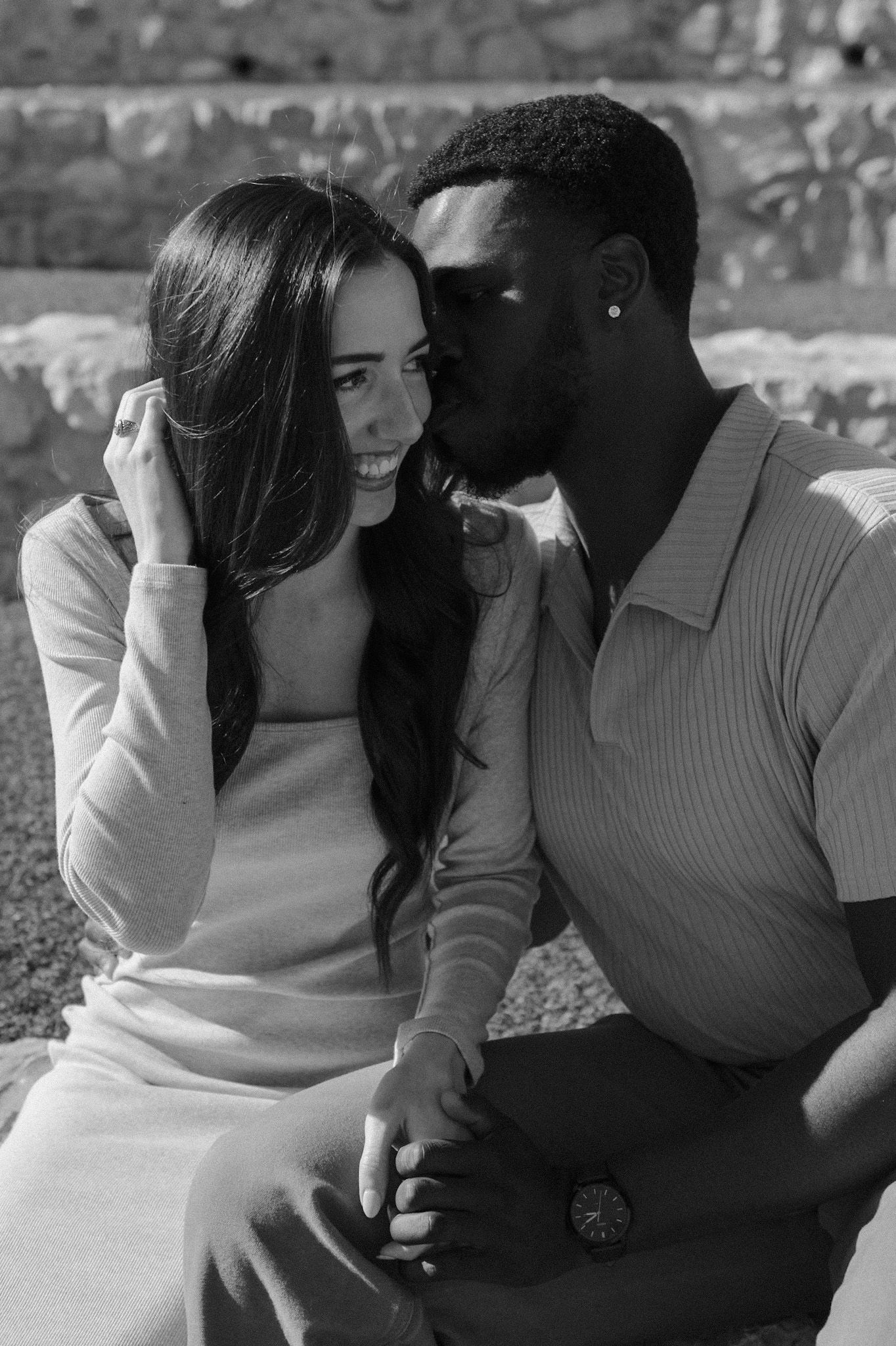 A couple shares tender moments while sitting together in black and white photography.