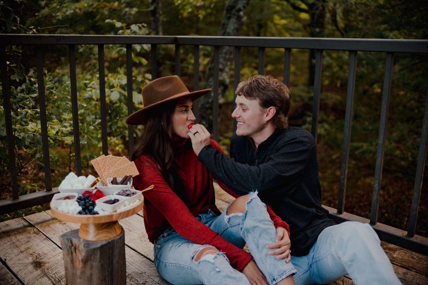 A romantic couple shares intimate moments on a wooden bridge surrounded by autumn foliage.