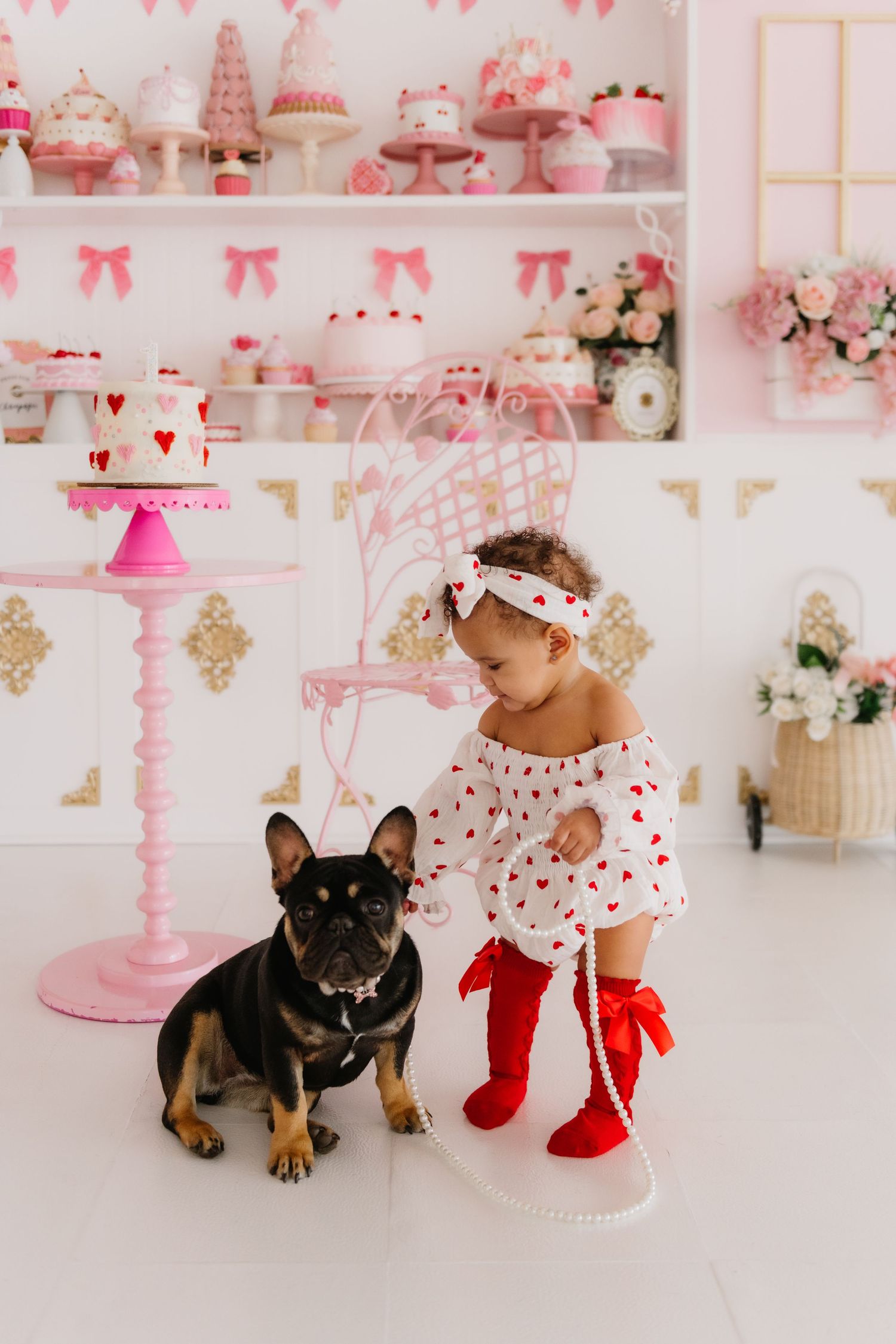 Baby and French Bulldog in pink and white decorated Valentine's Day setting.