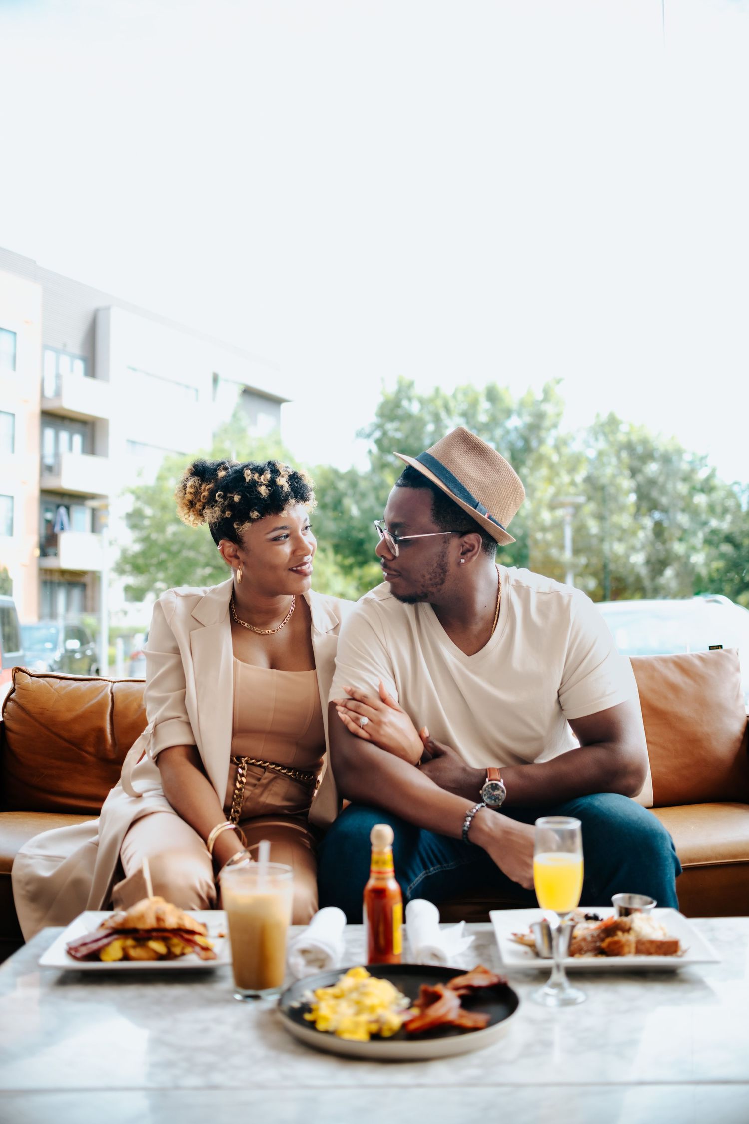 Couple sharing intimate moment over brunch with food and drinks on table.