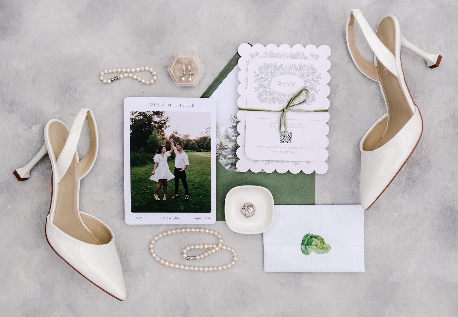 Wedding details including white shoes, invitations, and green accents arranged on a light gray surface.