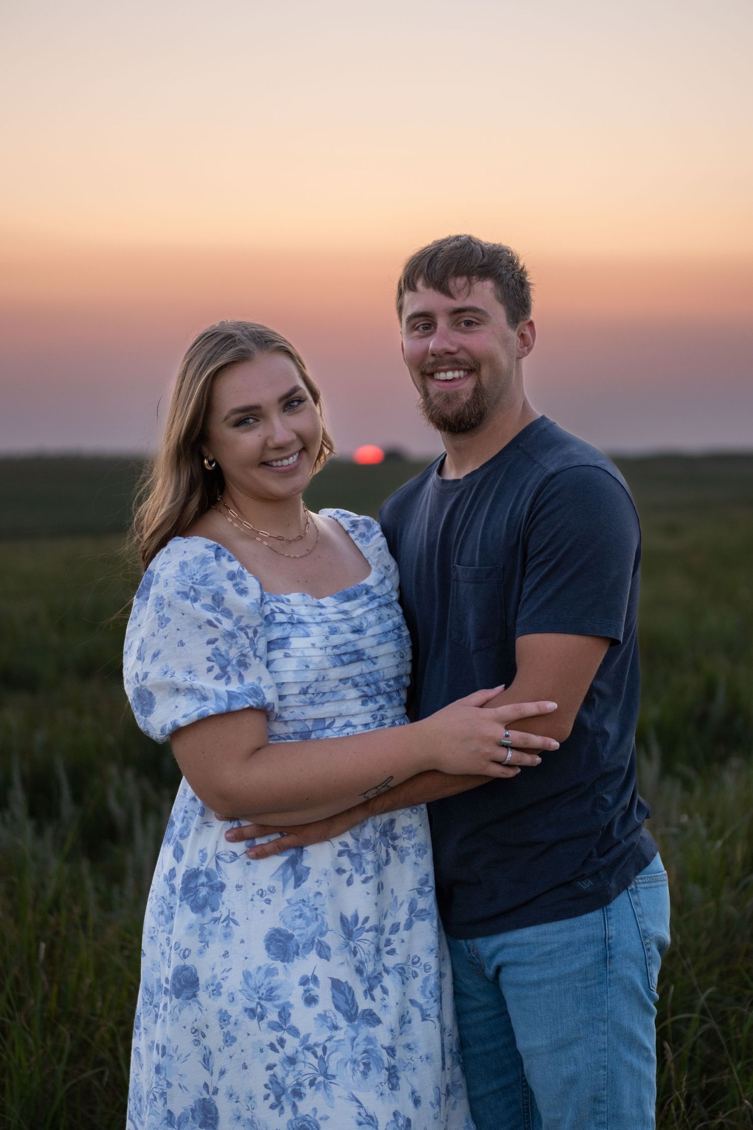 A couple shares a light hug while the sun sets behind them during a couples session.