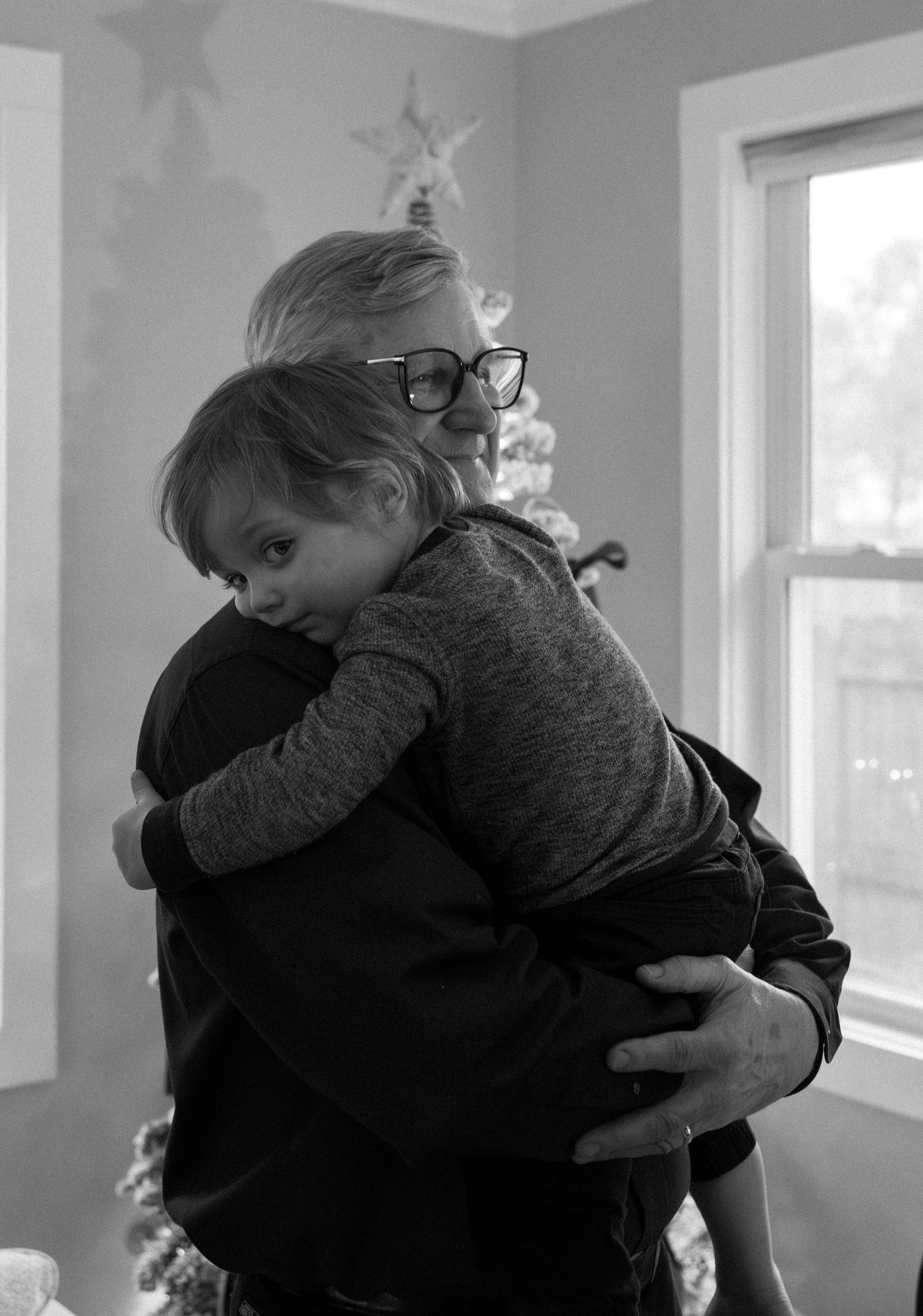 A heartwarming embrace next to a window with holiday decorations visible.