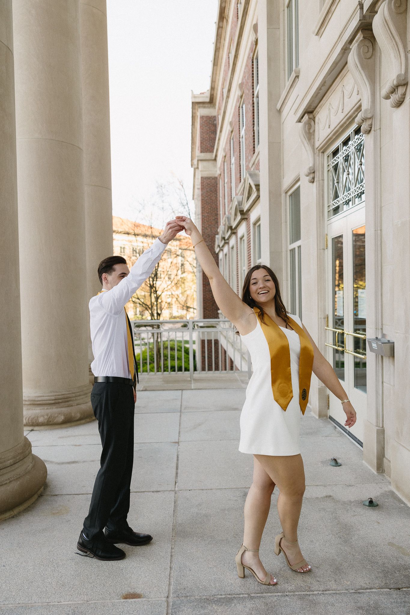 Two graduates dancing and celebrating between columns at Purdue University.