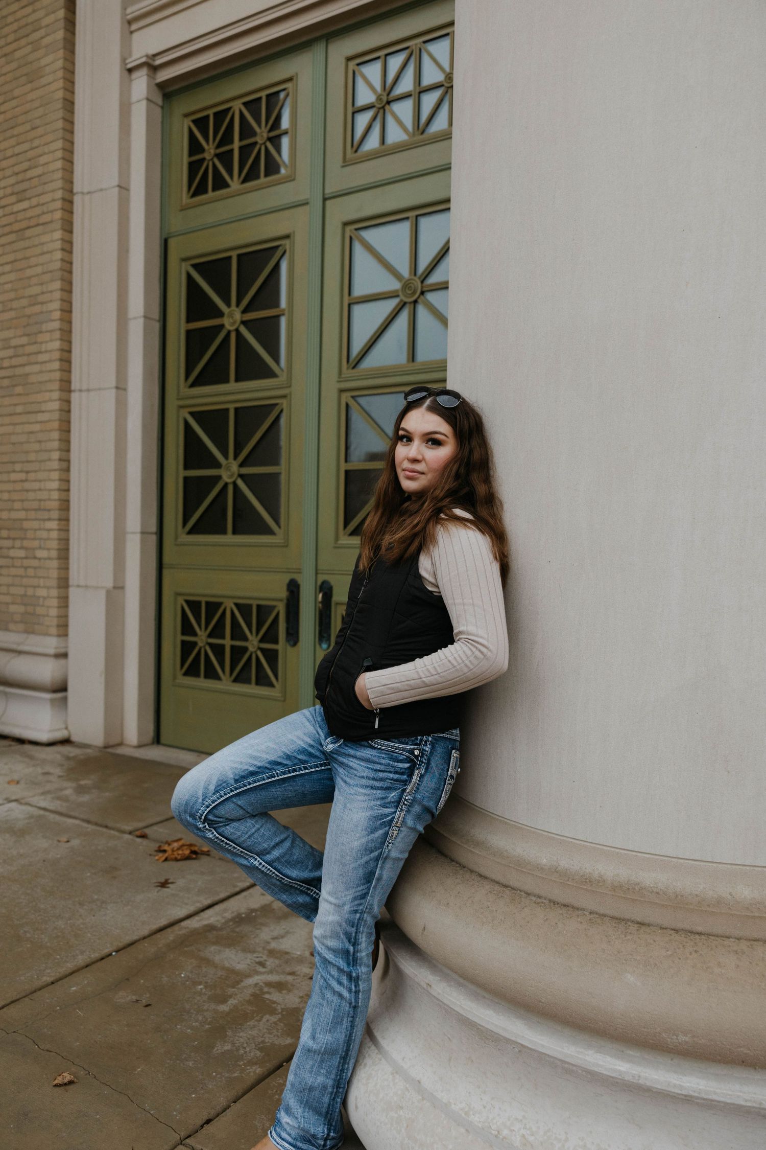 A fashion portrait against architectural columns featuring casual denim and knitwear.