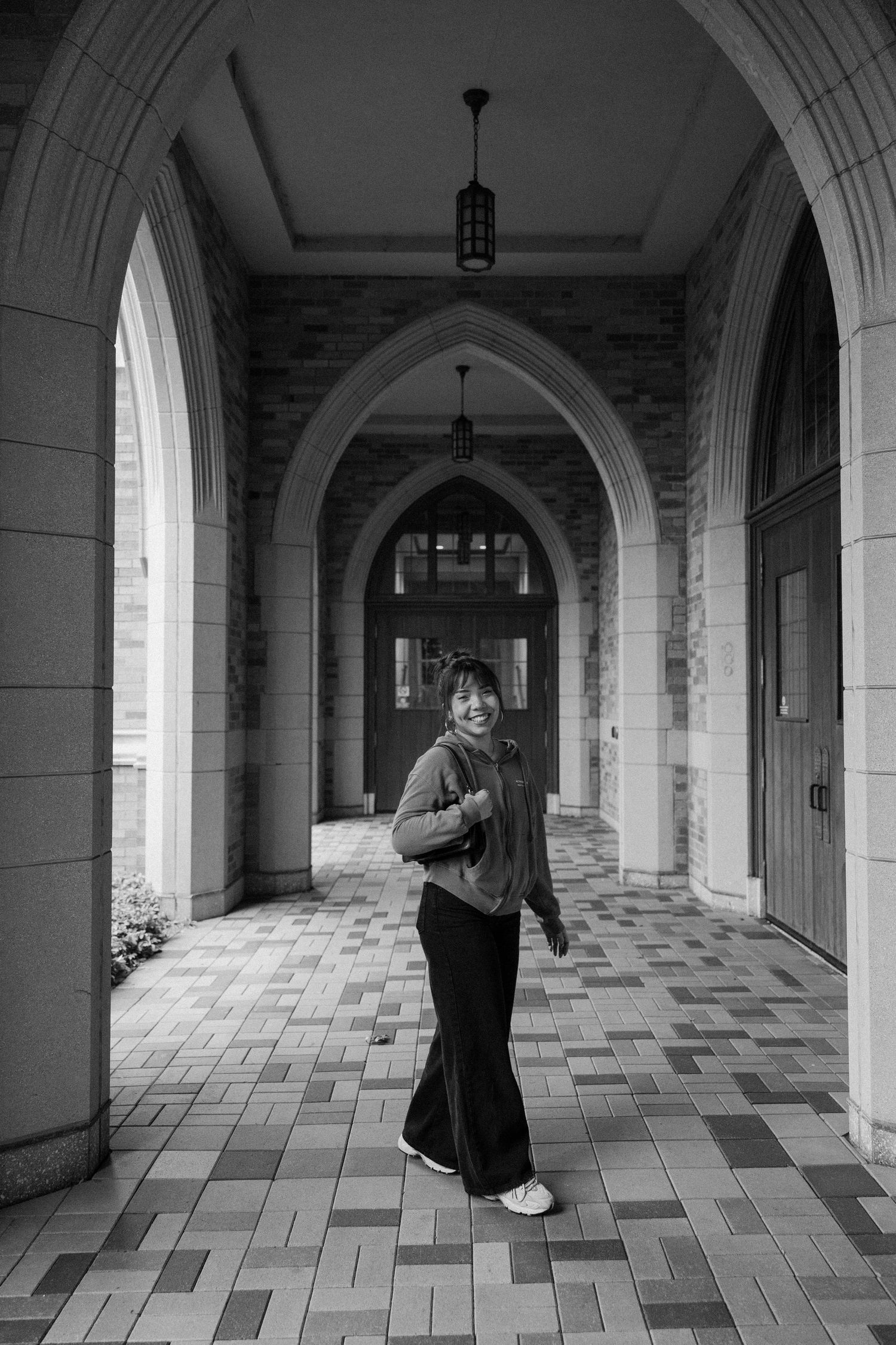 A black and white portrait under Gothic arches with patterned floor tiles.
