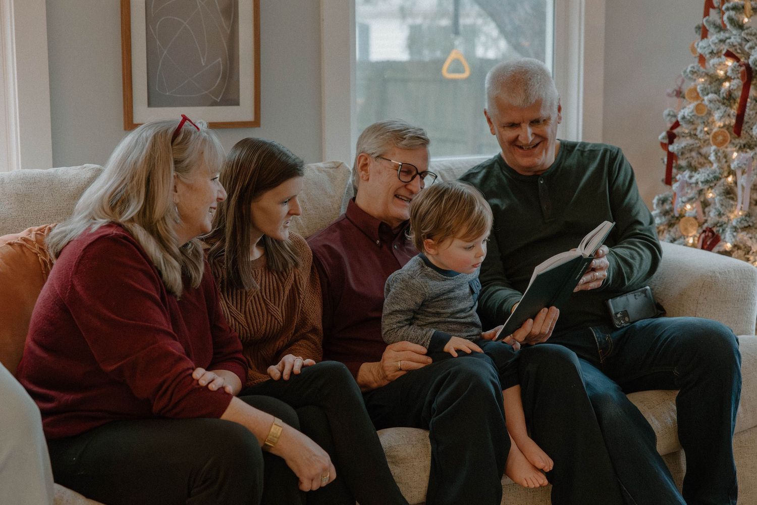 Multiple generations gather on a couch to look at a device during the holiday season.