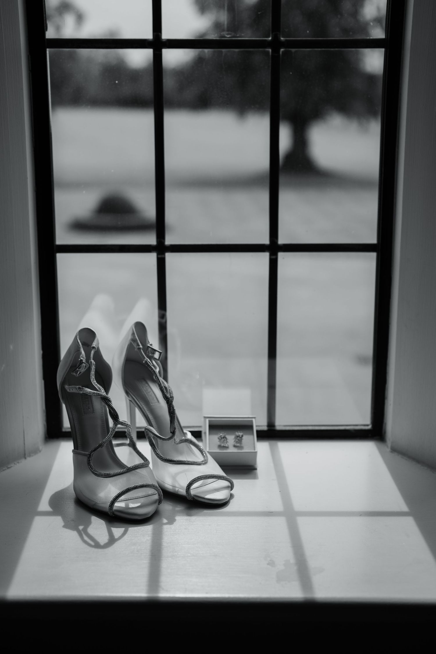 Wedding shoes placed by a window creating dramatic shadows and lighting.