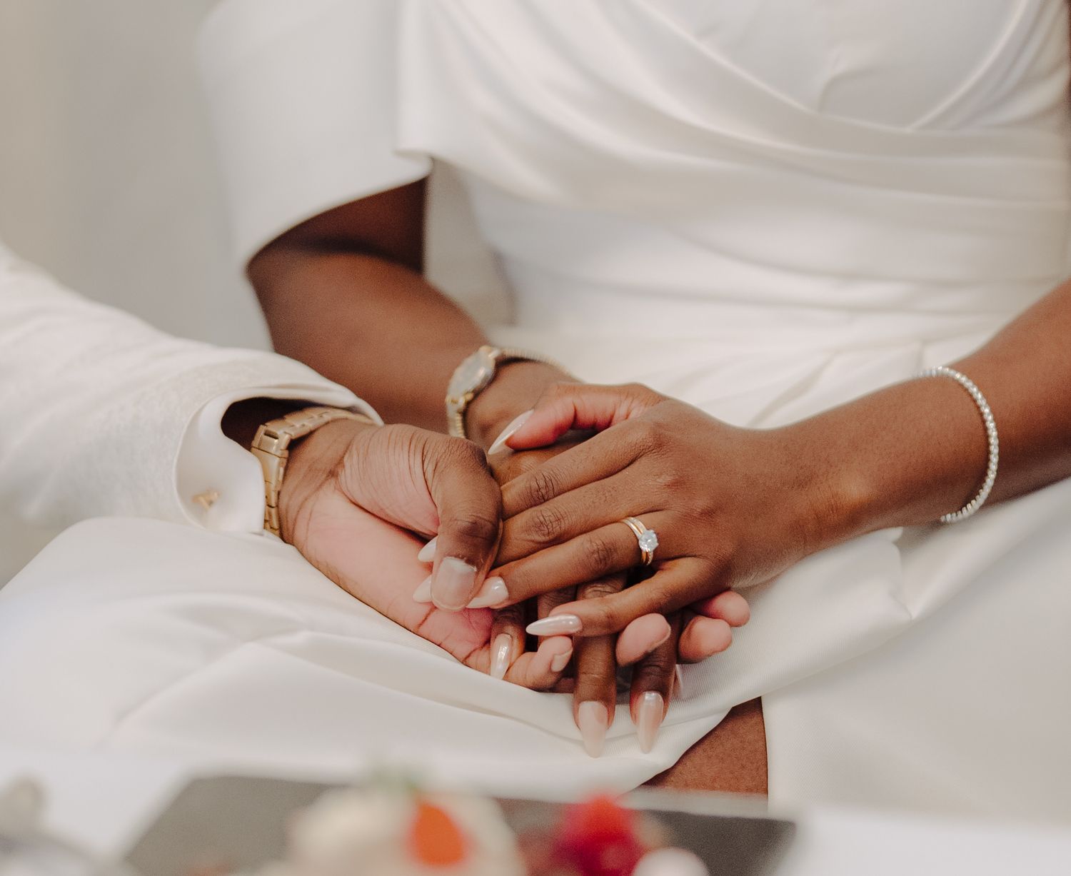 Close-up of hands with wedding rings against white fabric background.